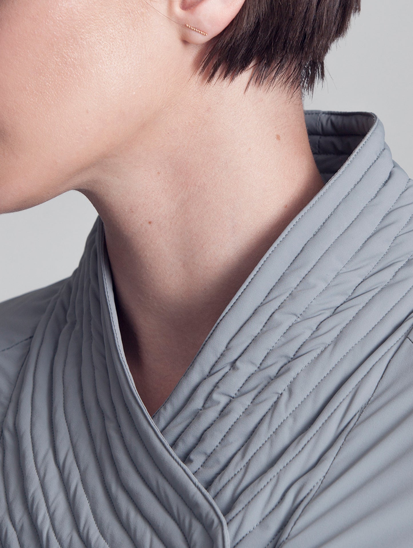 Woman wearing grey Passport Jacket from AETHER Apparel, displaying collar detail.