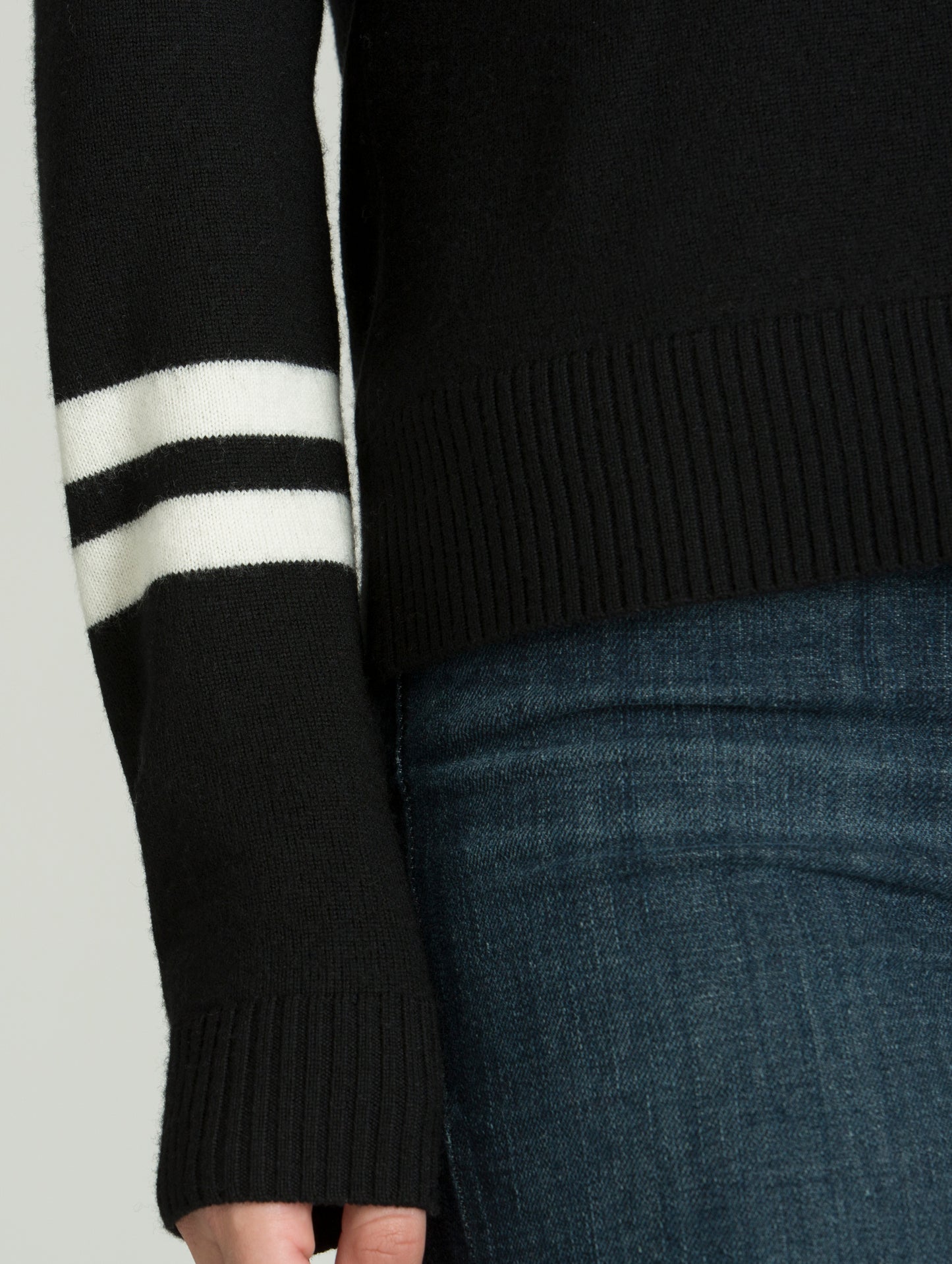 Closeup detailed view of contrasting stripes and knitted cuffs on women's Racer Sweater in Onyx Black from AETHER Apparel.