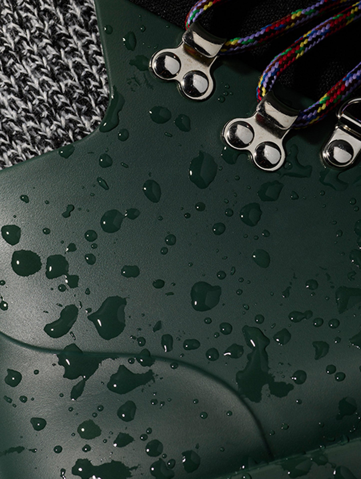 Closeup detailed view of metal speed lacing hooks and weatherproof uppers on women's Rain Boot in Dark Green from AETHER Apparel.