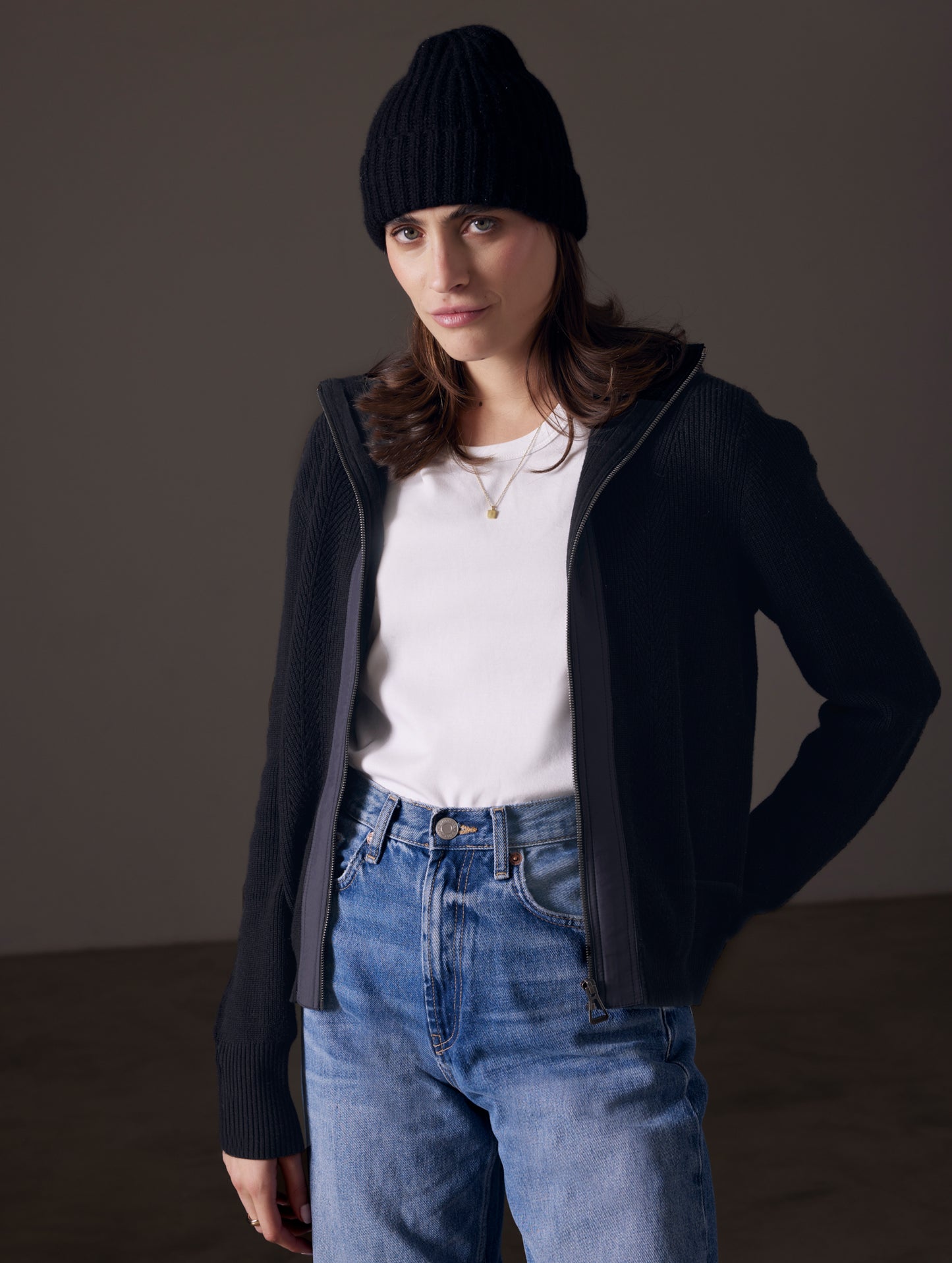 Front angled view of woman wearing unzipped Rhea Full-Zip Sweater in Onyx Black from AETHER Apparel.