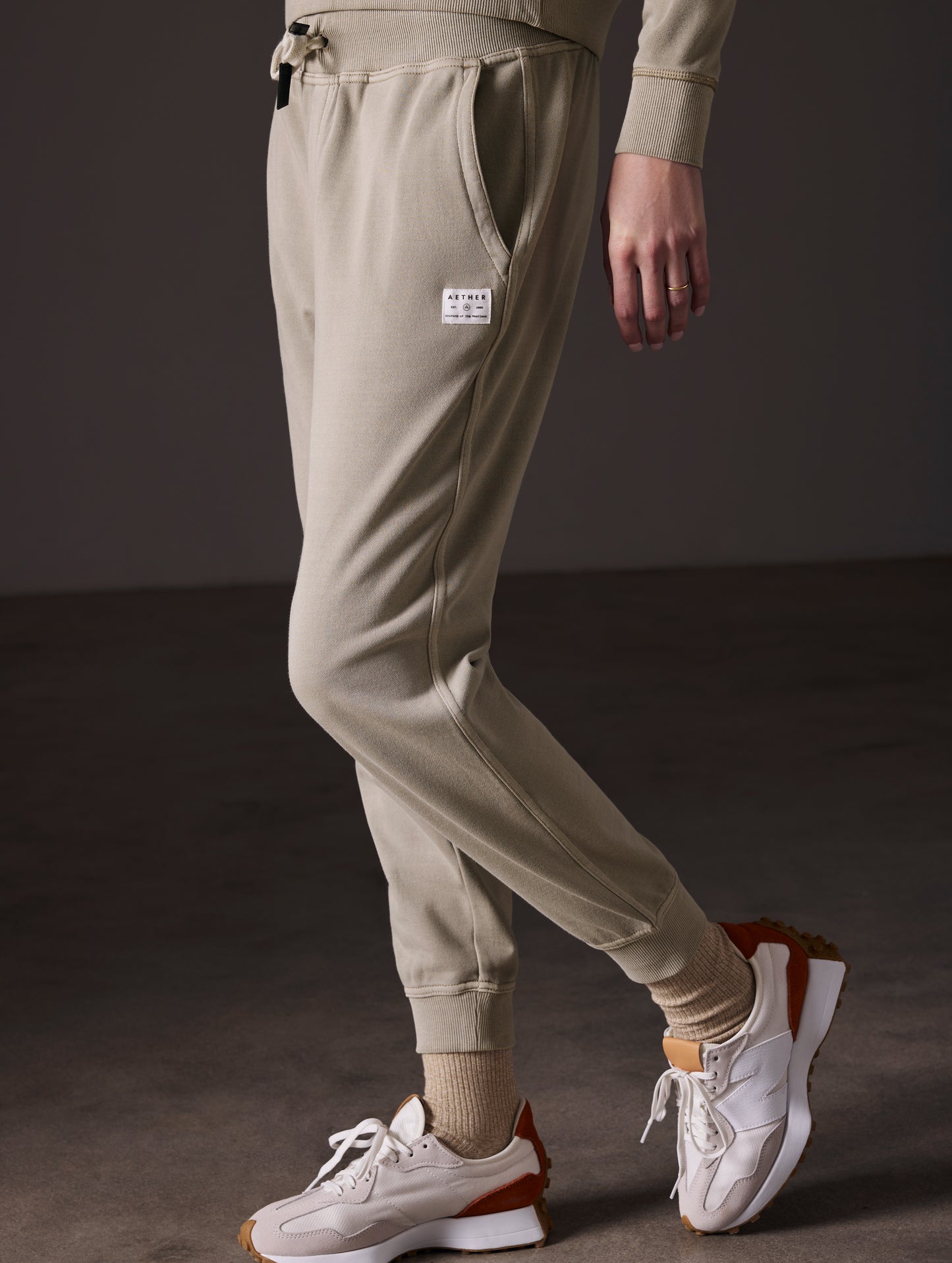 Side profile lower body view of woman wearing Solstice Lightweight Jogger in Laurel Grey from AETHER Apparel.