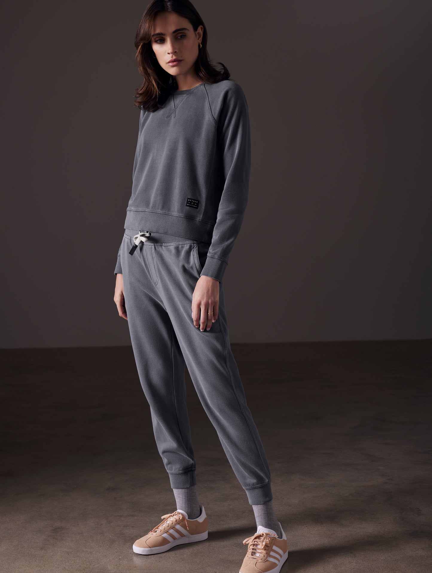 Front angled full-body view of woman wearing Solstice Lightweight Raglan Pullover in Graphite from AETHER Apparel.
