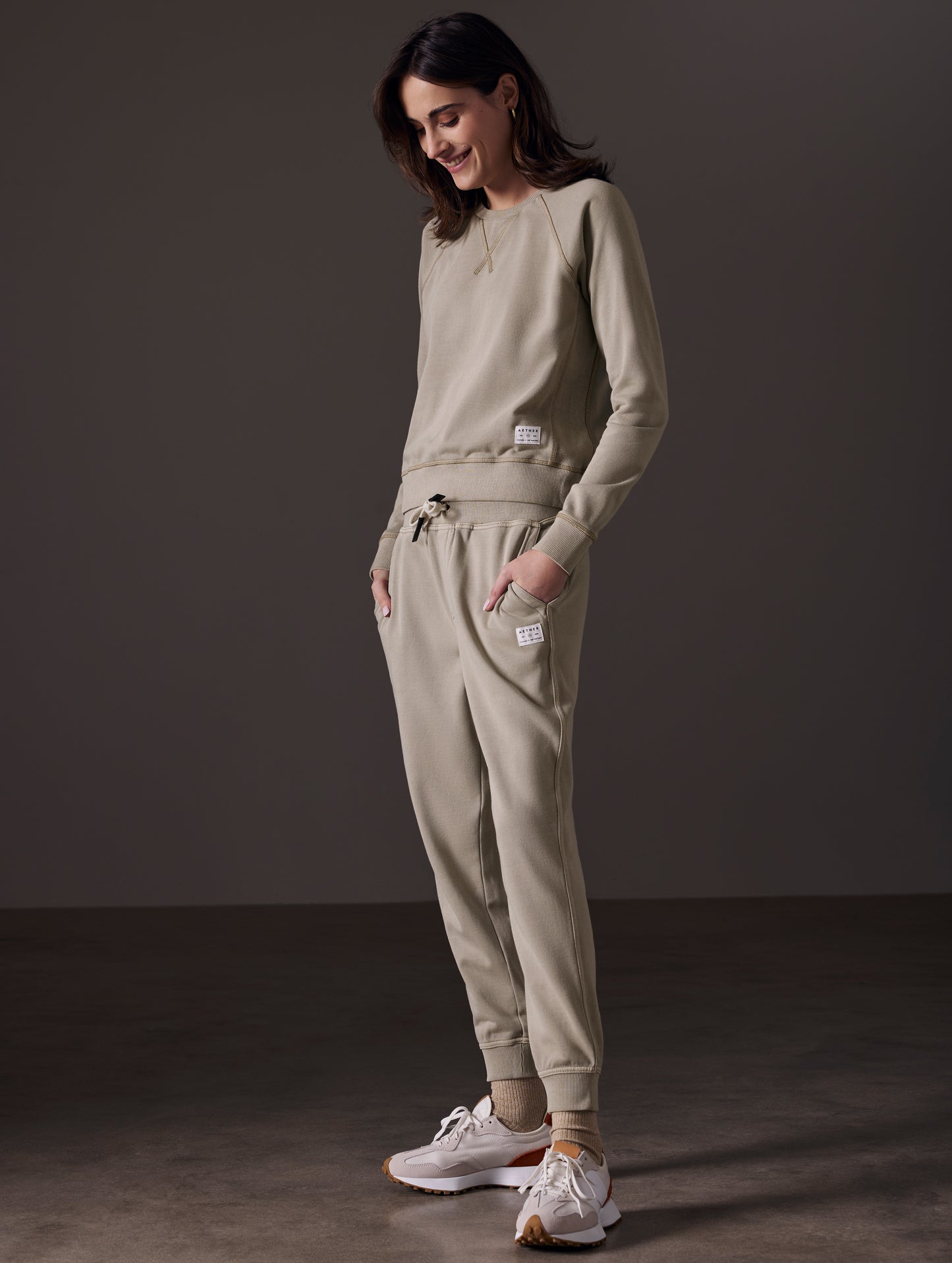 Front angled full-body view of woman wearing Solstice Lightweight Raglan Pullover in Laurel Grey from AETHER Apparel.