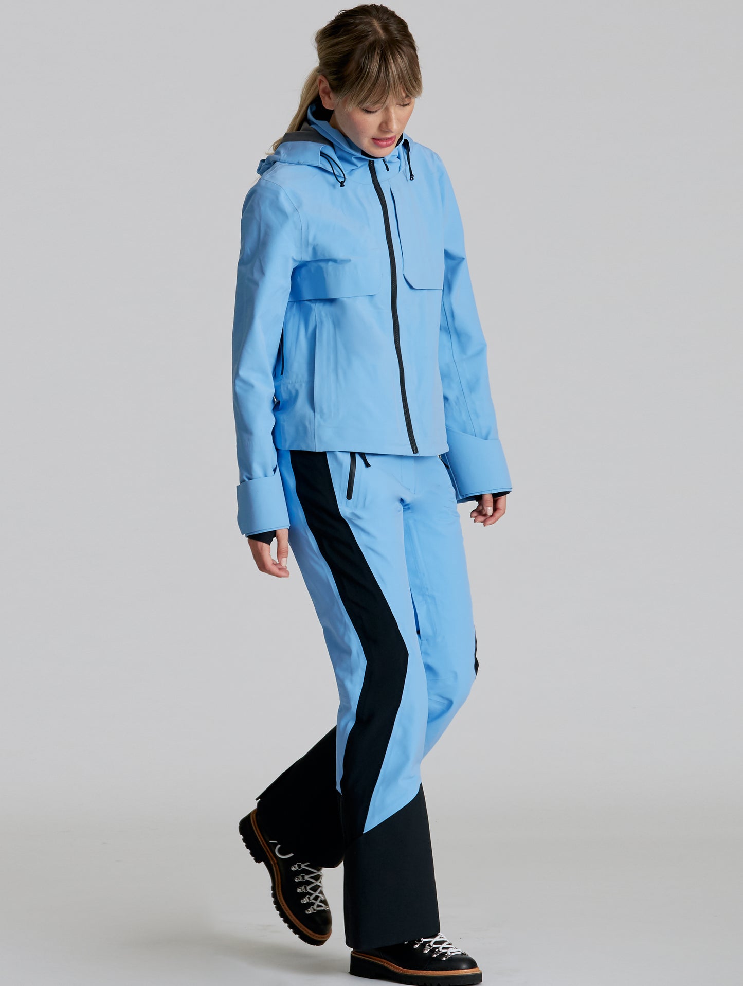 Front angled full-body view of woman wearing Stealth Snow Pant in Atlas Blue and Onyx Black from AETHER Apparel.