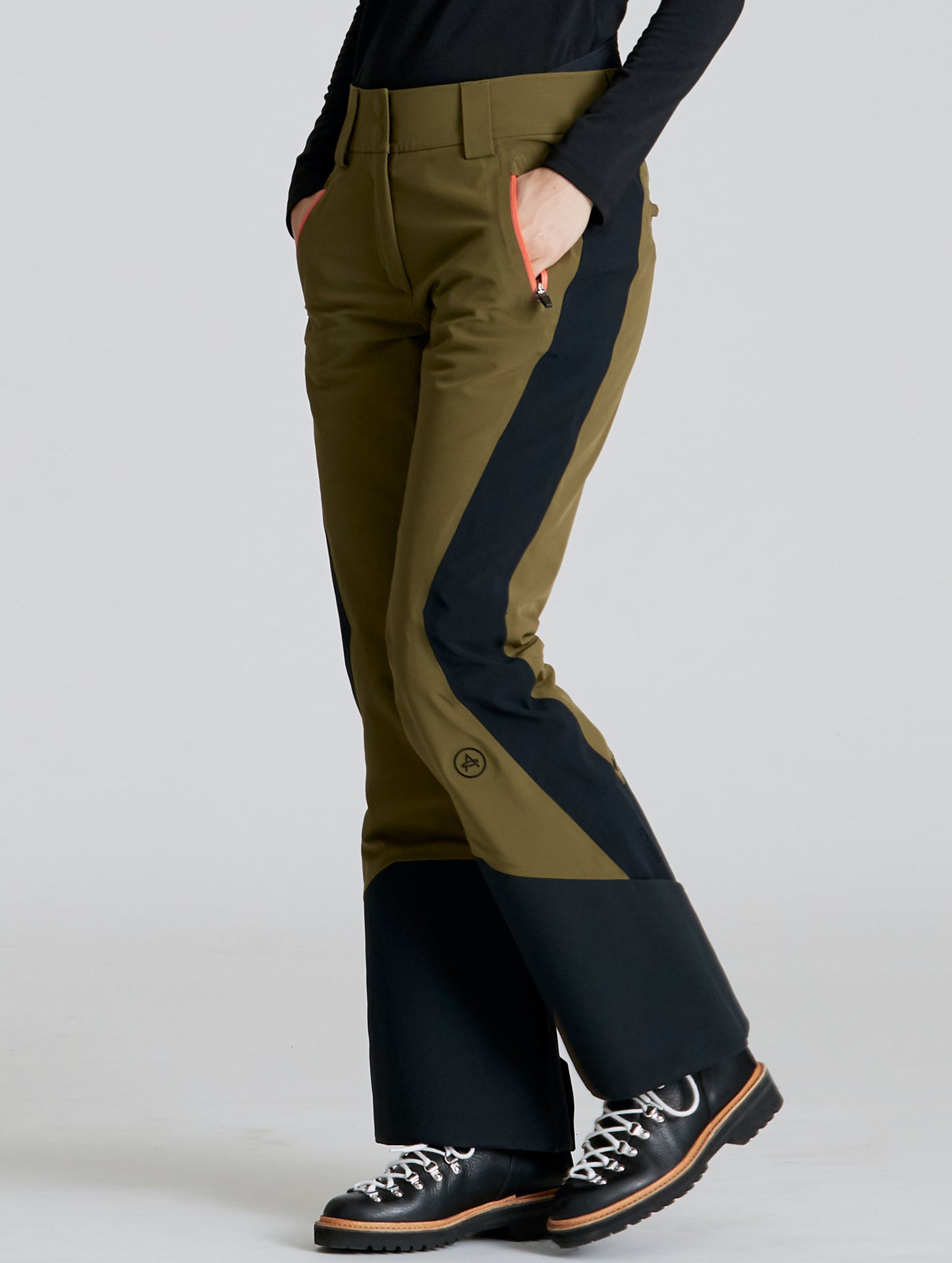 Front angled lower body view of woman wearing Stealth Snow Pant in Command Green and Onyx Black from AETHER Apparel.