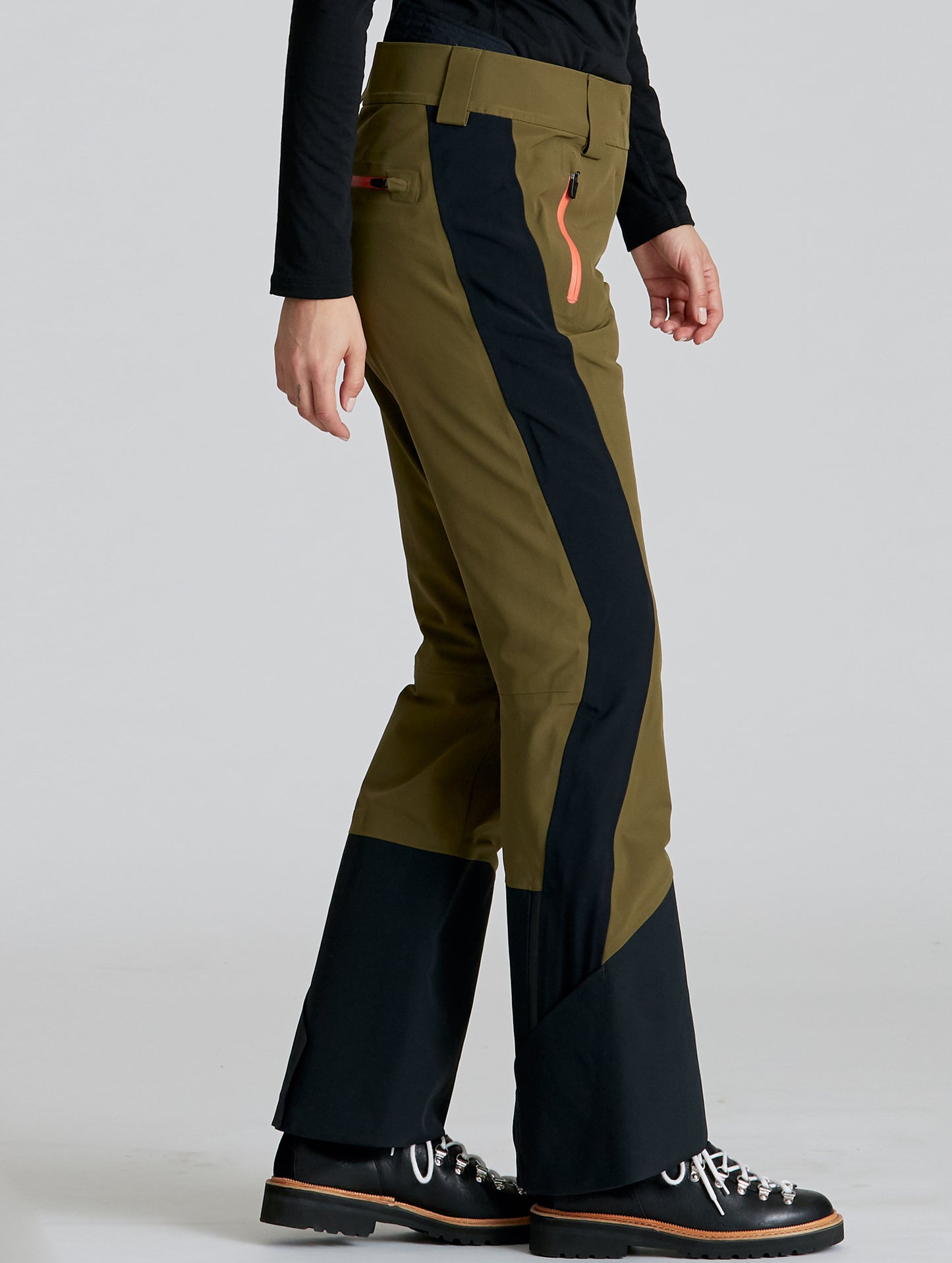 Side profile lower-body view of woman wearing Stealth Snow Pant in Command Green and Onyx Black from AETHER Apparel.
