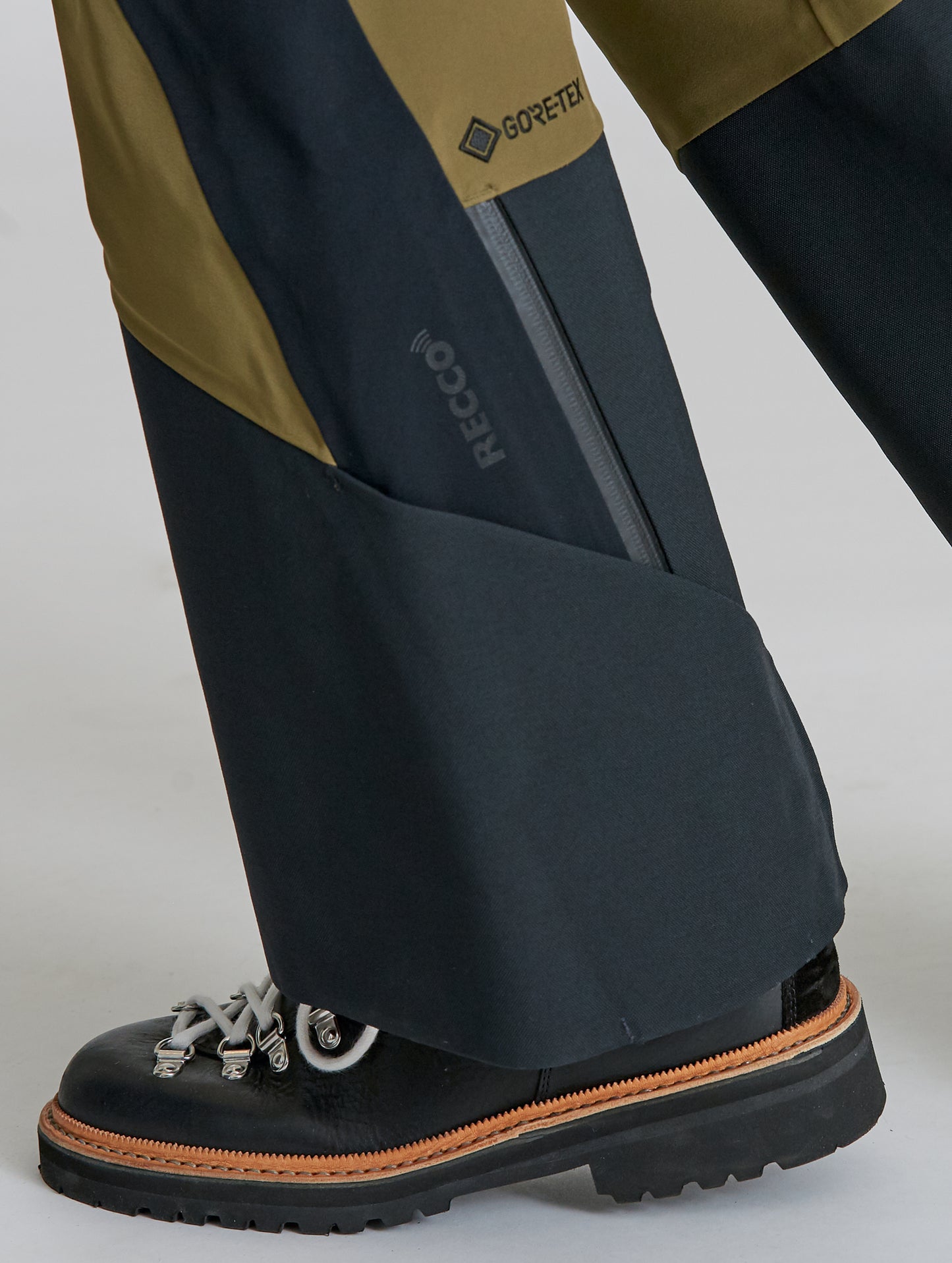 Closeup detailed view of leg cuff and RECCO and GORE-TEX logos on Stealth Snow Pant in Command Green and Onyx Black from AETHER Apparel.