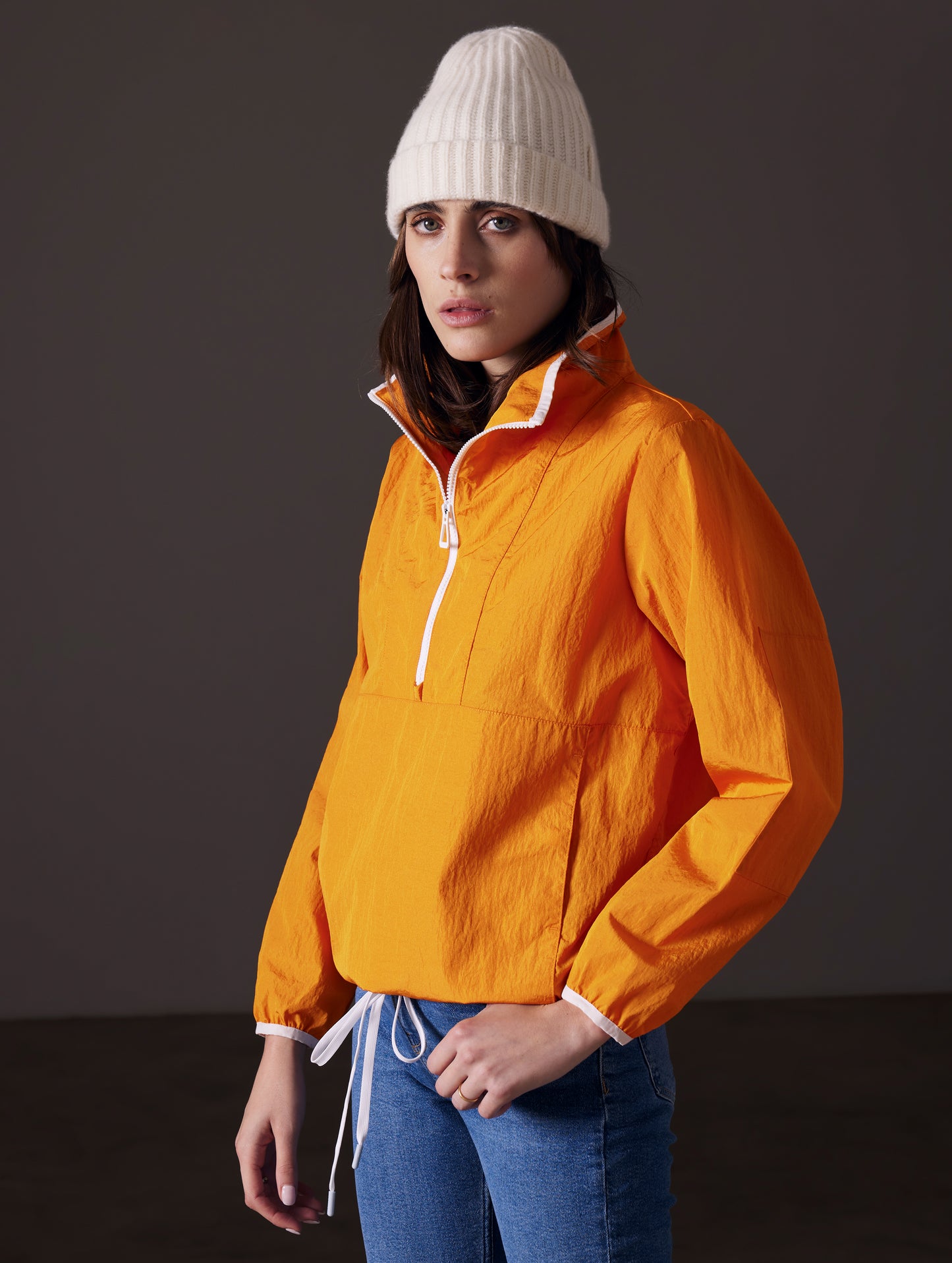Front angled view of woman wearing Topanga Lightweight Anorak in Midas Orange from AETHER Apparel.