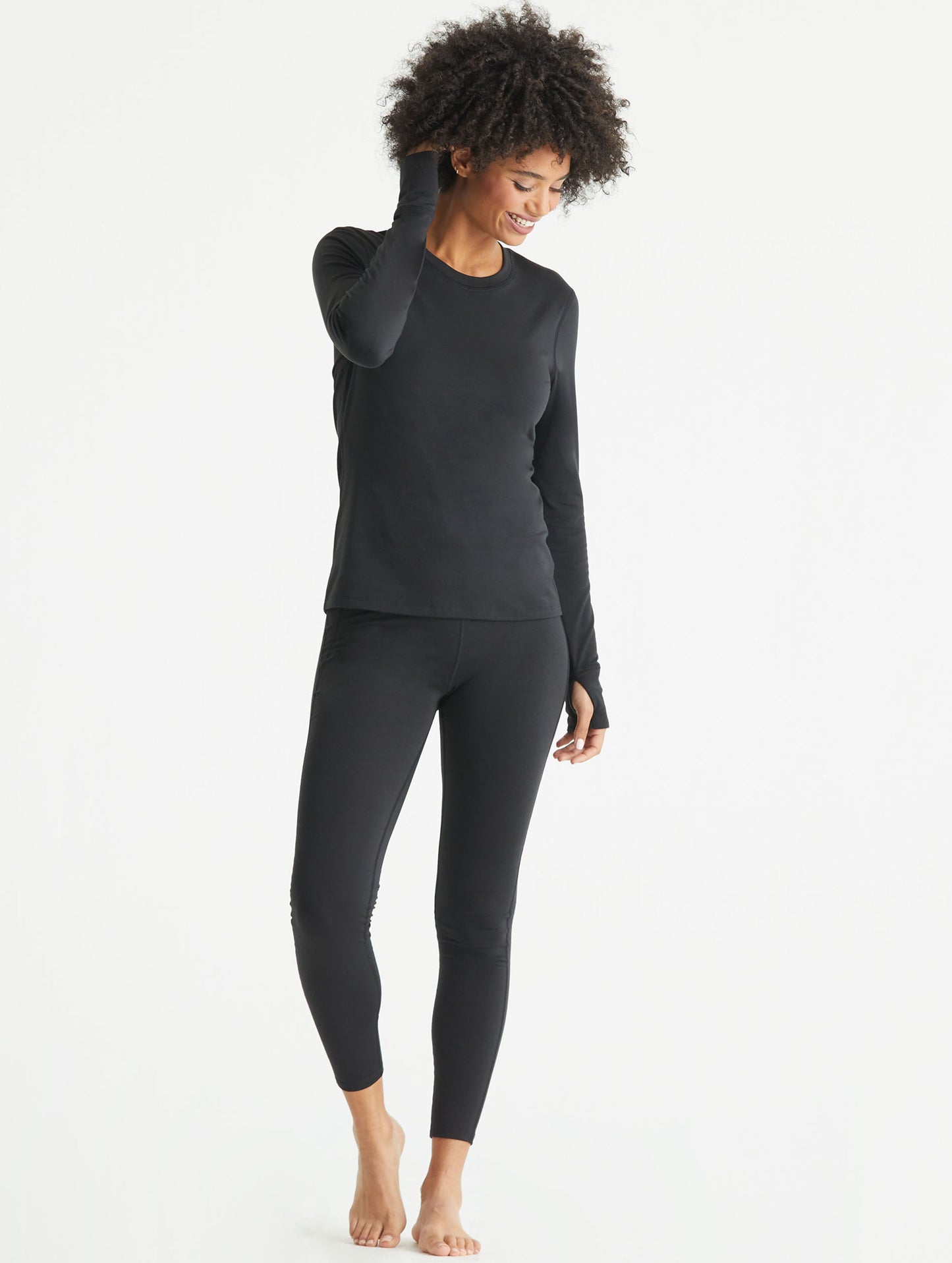 Full-body view of woman wearing black Vapor Base Layer long-Sleeve shirt from AETHER Apparel.