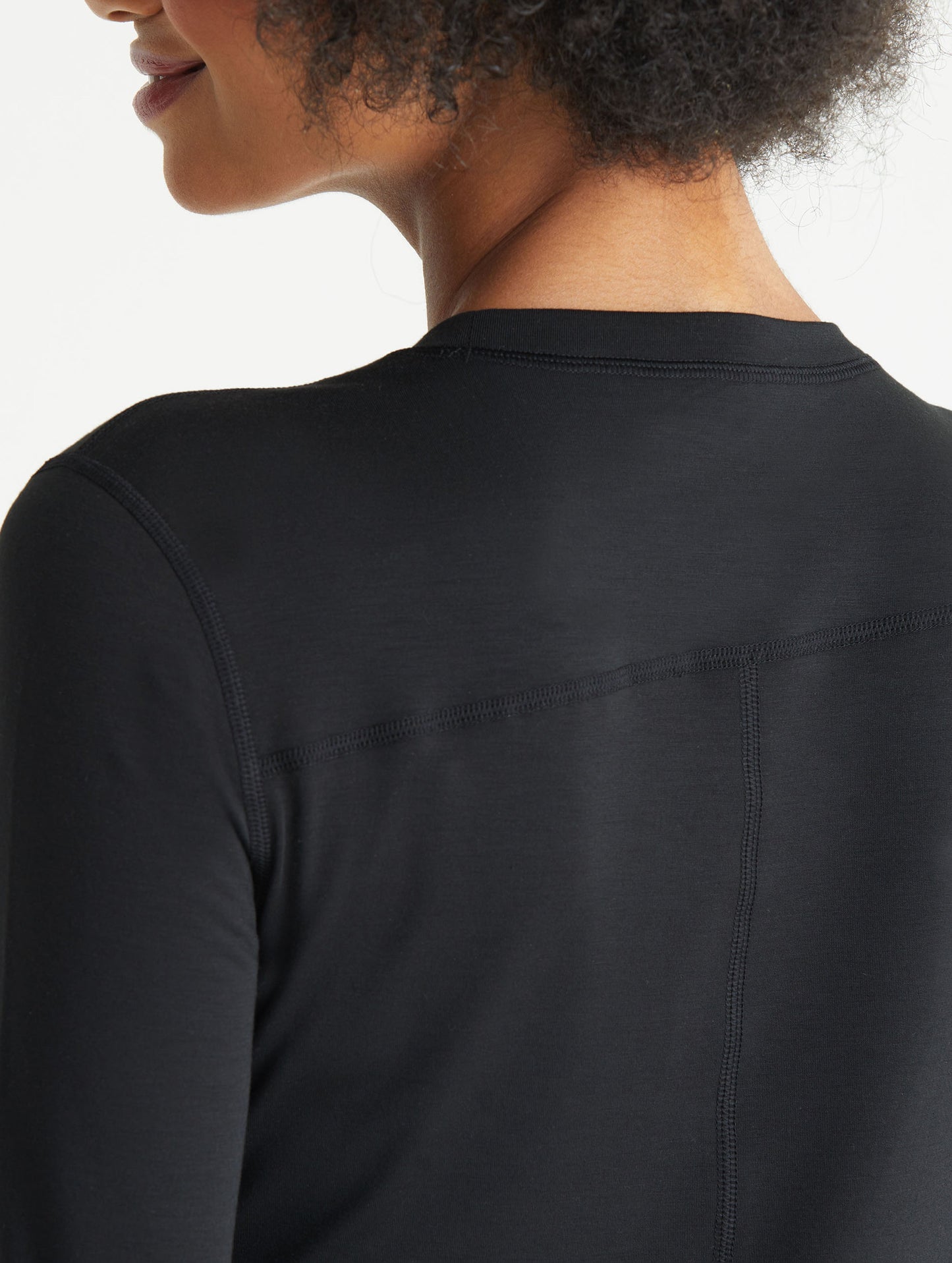 Back view of woman wearing black Vapor Base Layer long-Sleeve shirt from AETHER Apparel.