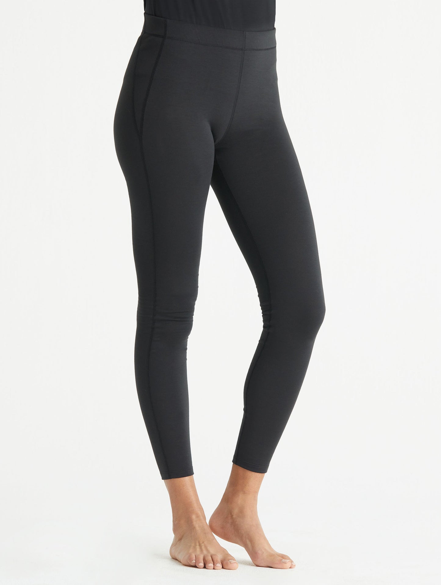 Front 3/4 view of woman wearing black Vapor Base Layer Pant from AETHER Apparel.