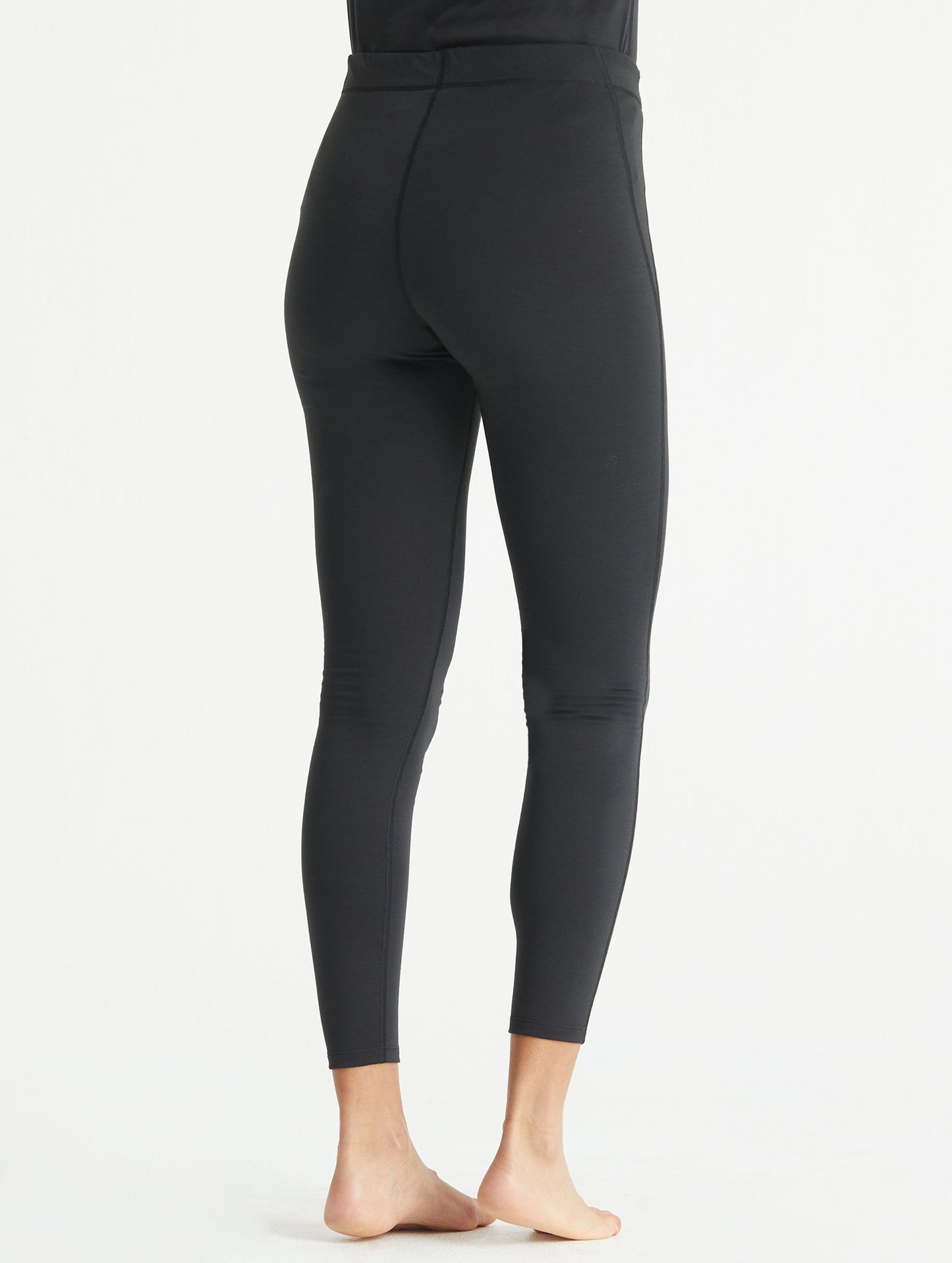 Back view of woman wearing black Vapor Base Layer Pant from AETHER Apparel.