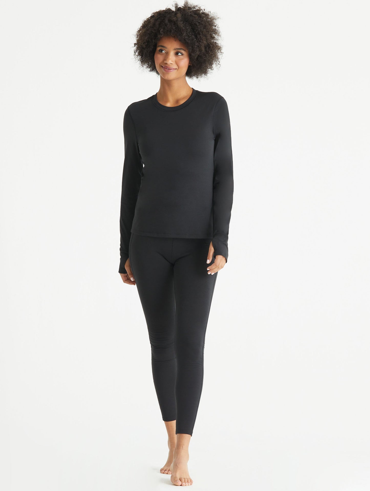 Front full-body view of woman wearing black Vapor Base Layer Pant from AETHER Apparel.