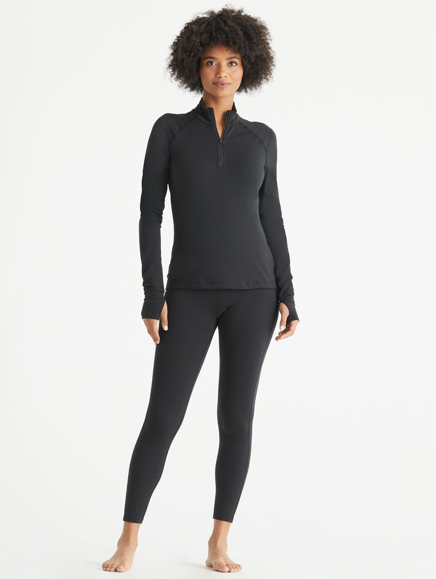 Full-body view of woman wearing black Vapor Half-Zip Base Layer Jacket from AETHER Apparel.
