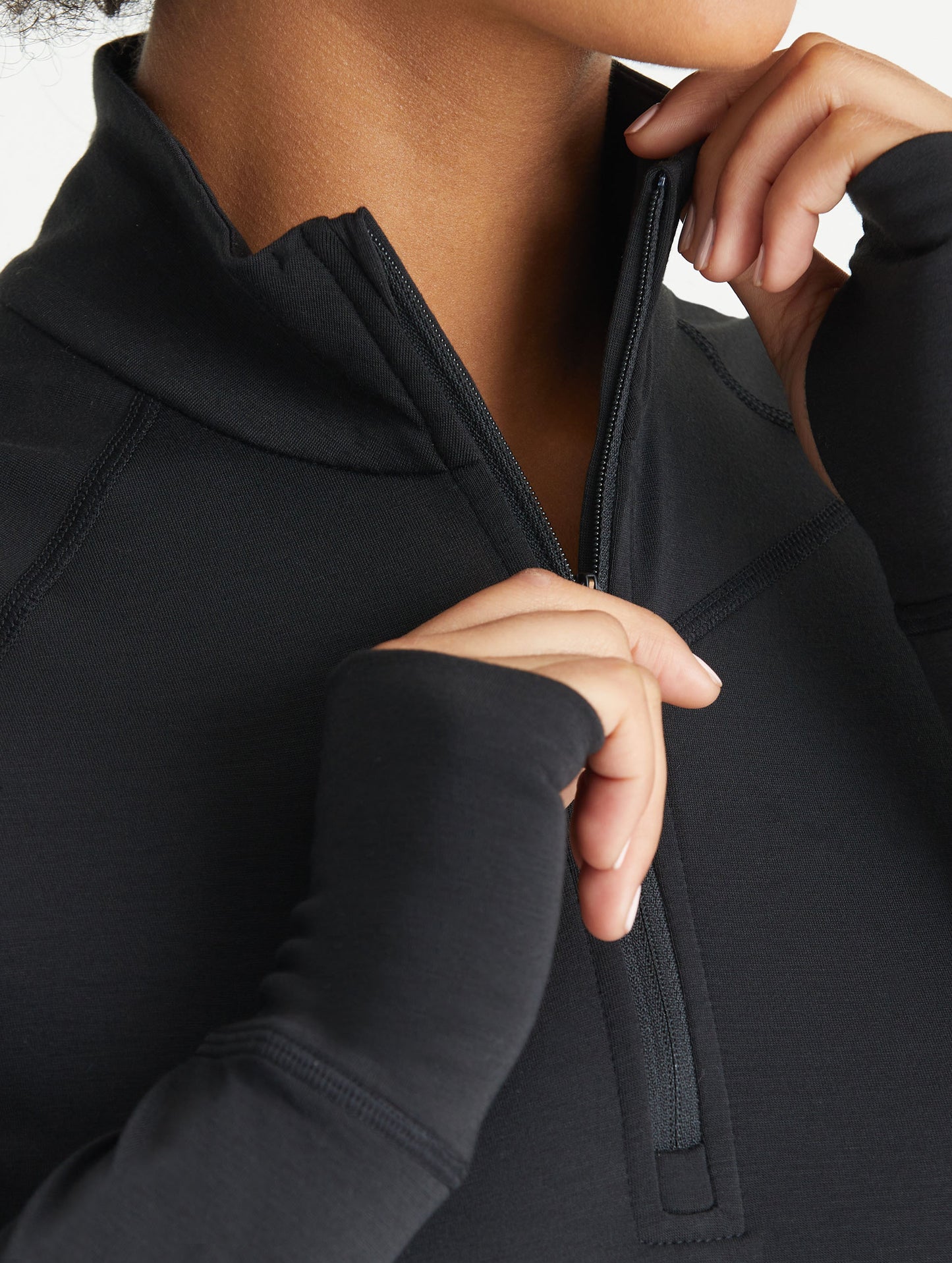 Zipper close-up of woman wearing black Vapor Half-Zip Base Layer Jacket from AETHER Apparel.