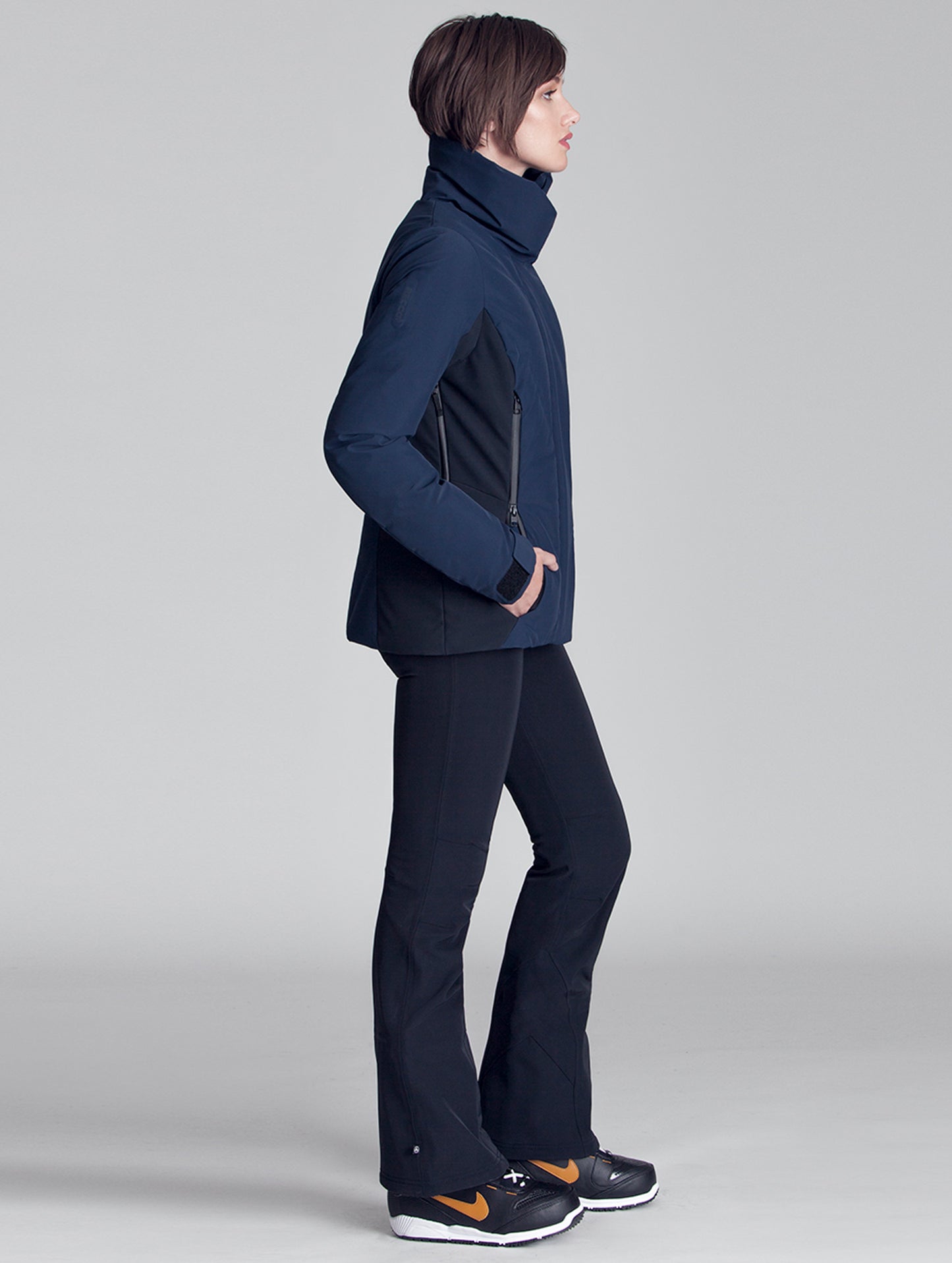 Side view of woman wearing blue Vertical Jacket from AETHER Apparel.