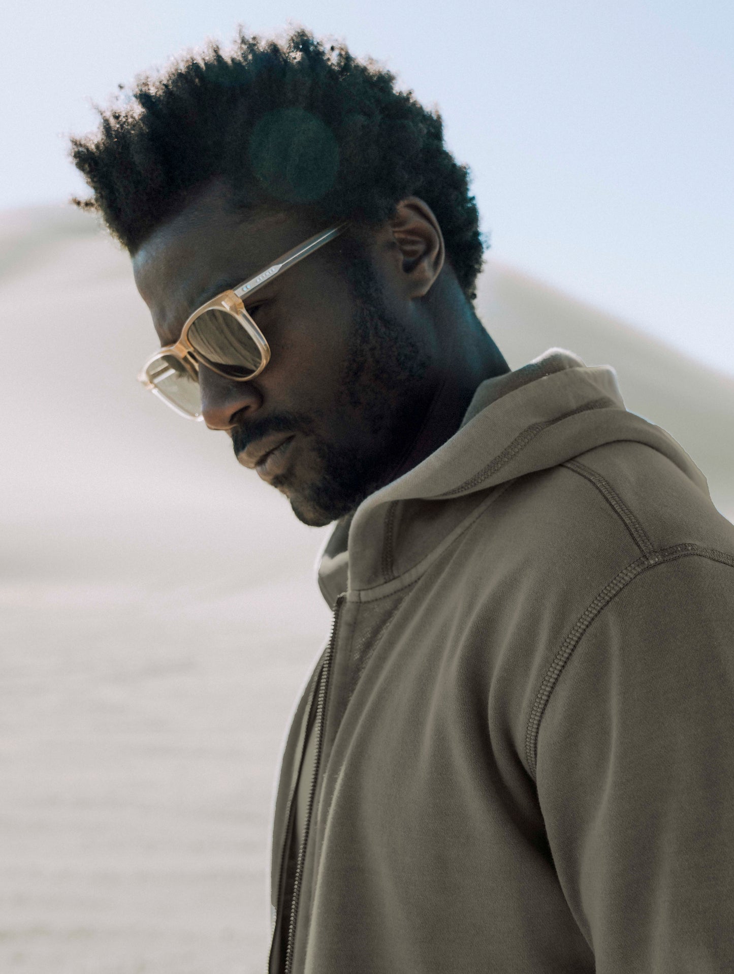 Outdoor lifestyle image of man in sand dunes wearing Yosemite Sunglass from AETHER Apparel.