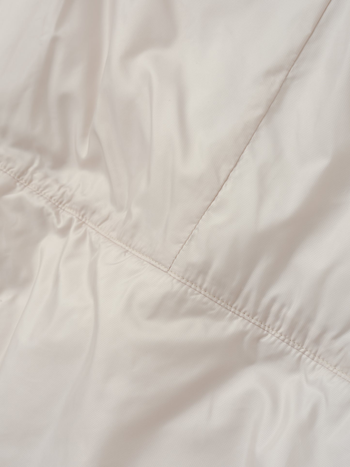 Closeup detailed view of the back seam on the Celeste Eco Insulated Vest in Bone from AETHER Apparel.