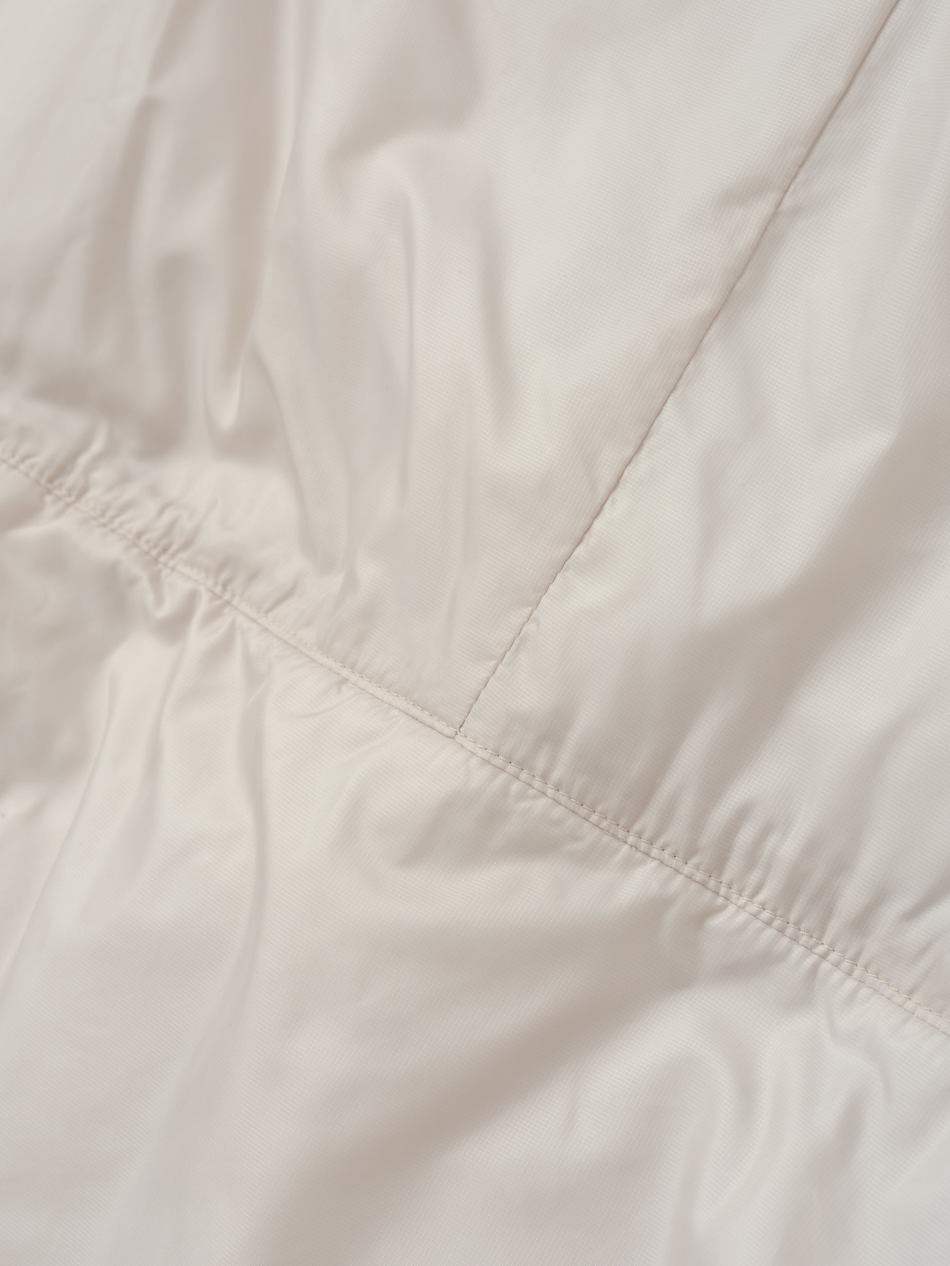 Closeup detailed view of the back seam on the Celeste Eco Insulated Vest in Bone from AETHER Apparel.