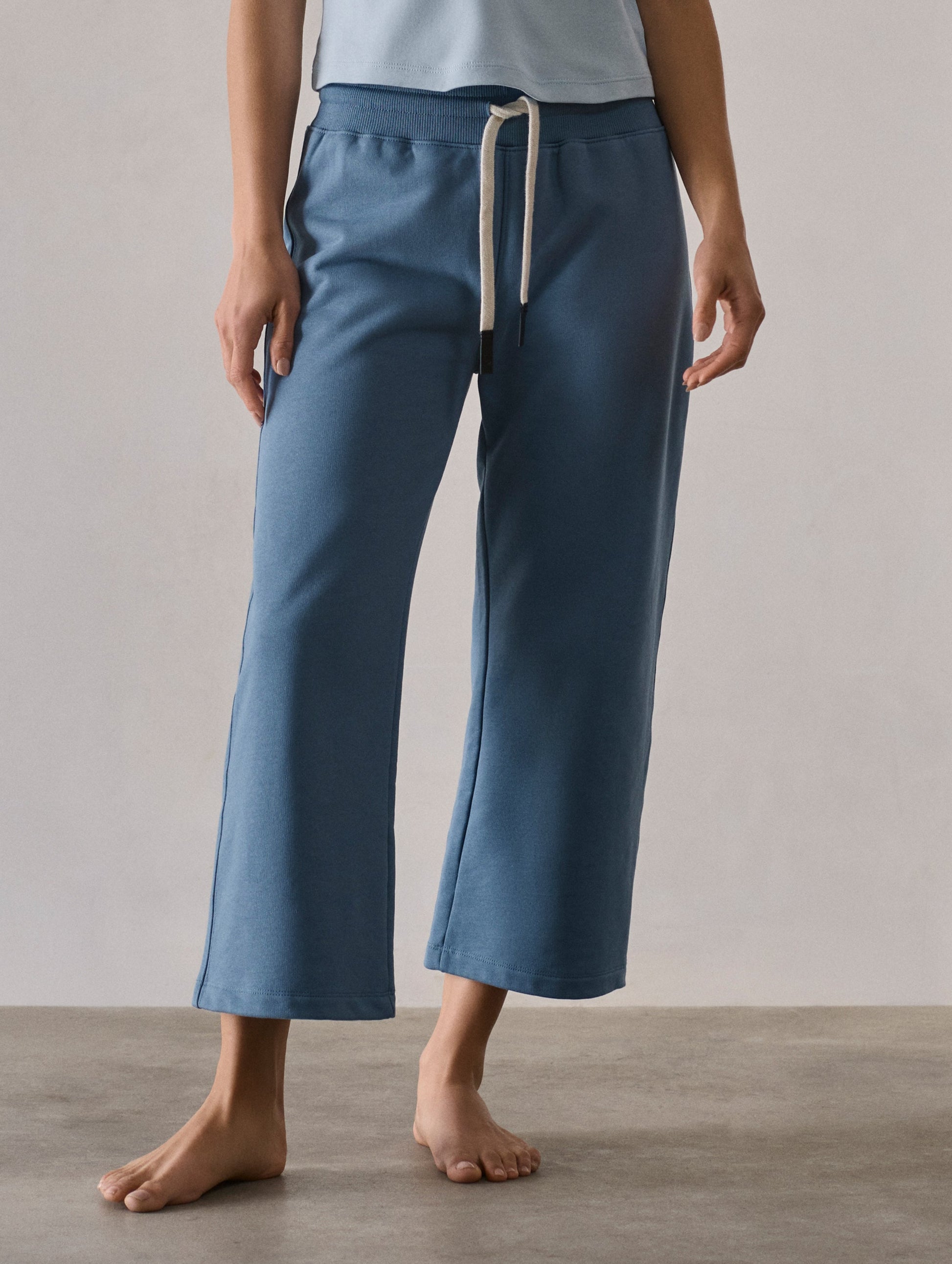Front full-body view of woman wearing W Osa Cropped Sweatpant in Coastal Blue from AETHER Apparel.