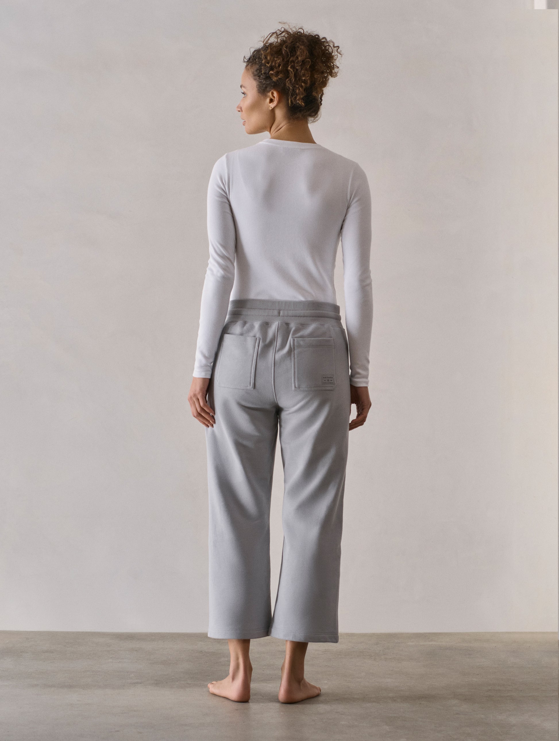 Rear full-body view of woman wearing W Osa Cropped Sweatpant in Sky Grey from AETHER Apparel.