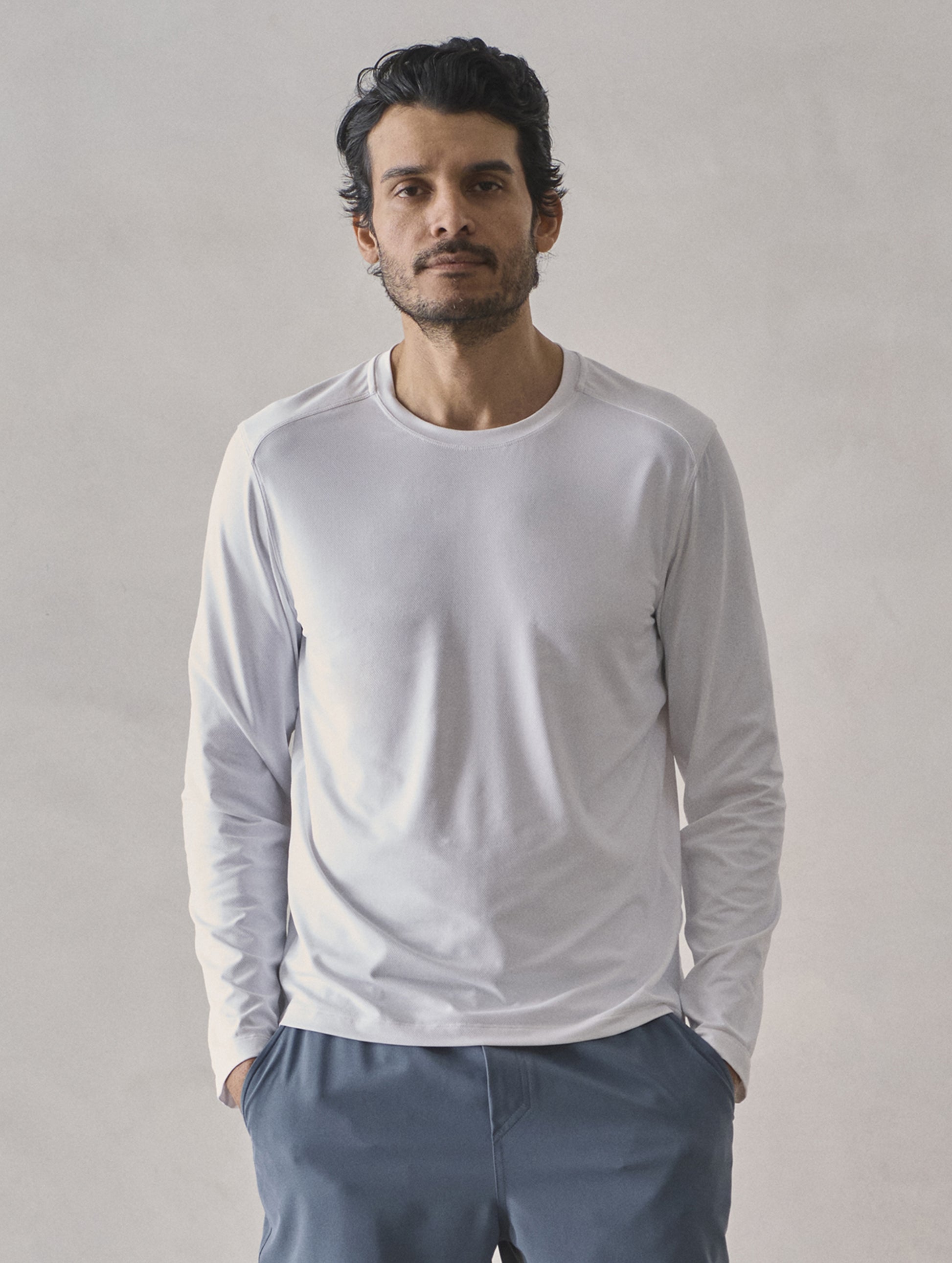 Front upper-body view of man wearing Adventure Performance Long-Sleeve Tee in White from AETHER Apparel.