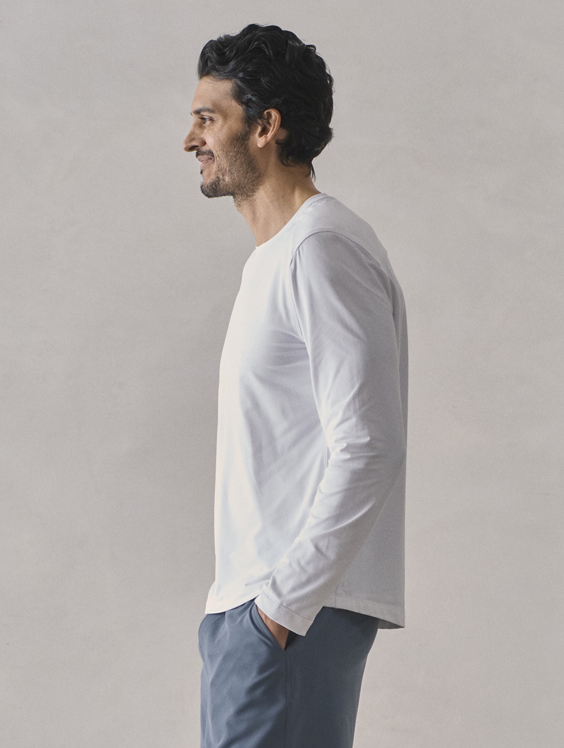 Side profile upper-body view of man wearing Adventure Performance Long-Sleeve Tee in White from AETHER Apparel.