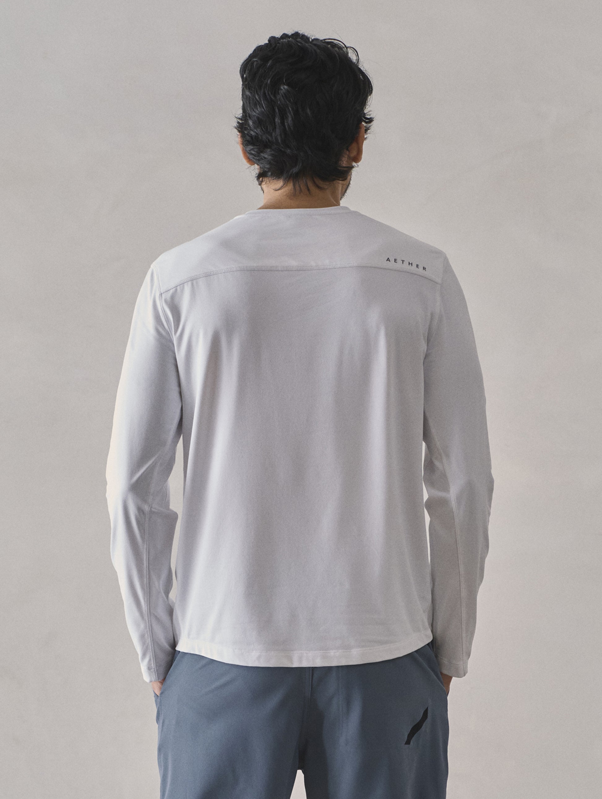 Rear upper-body view of man wearing Adventure Performance Long-Sleeve Tee in White from AETHER Apparel.