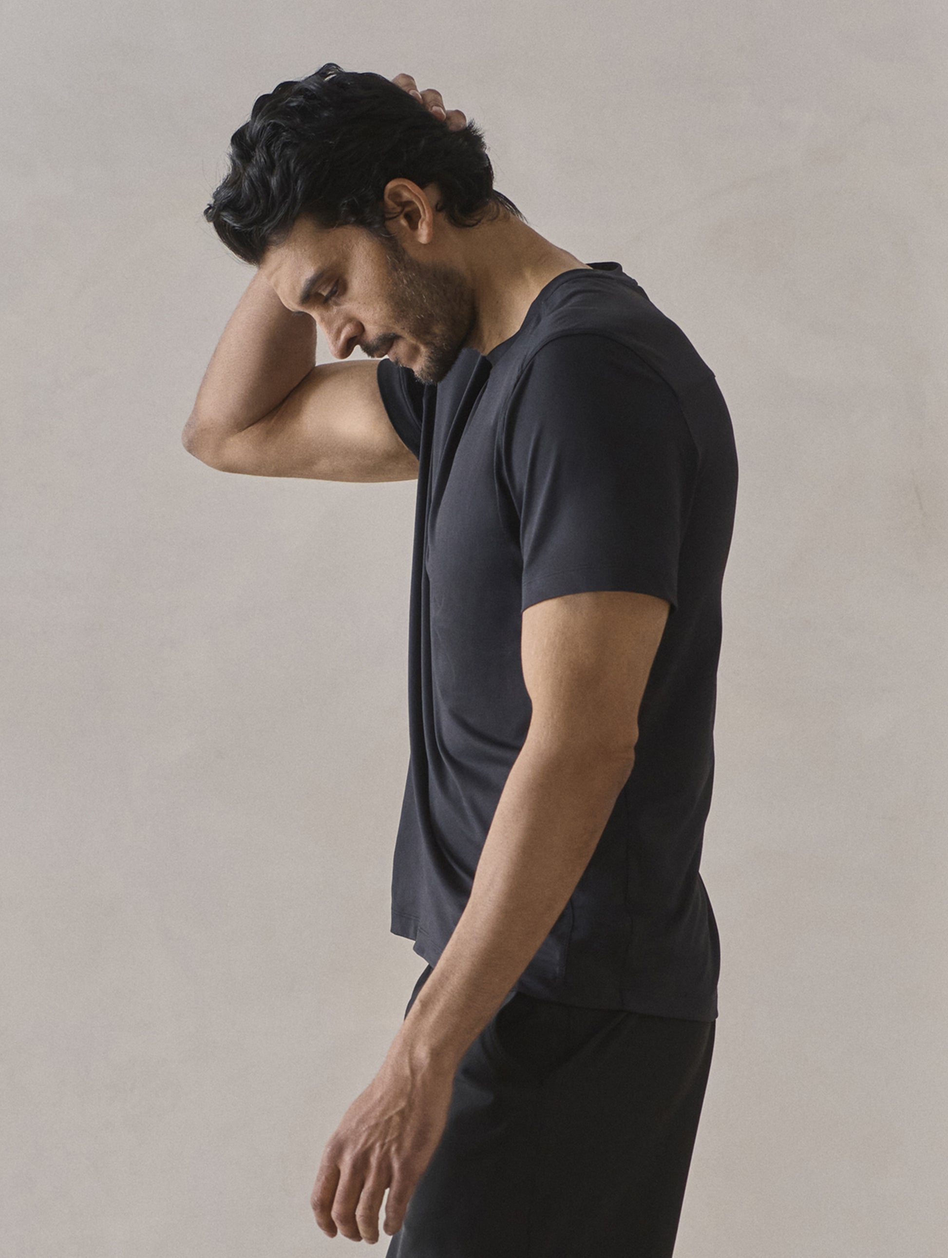 Side profile upper-body view of man wearing Adventure Performance Short-Sleeve Tee in Onyx Black from AETHER Apparel.