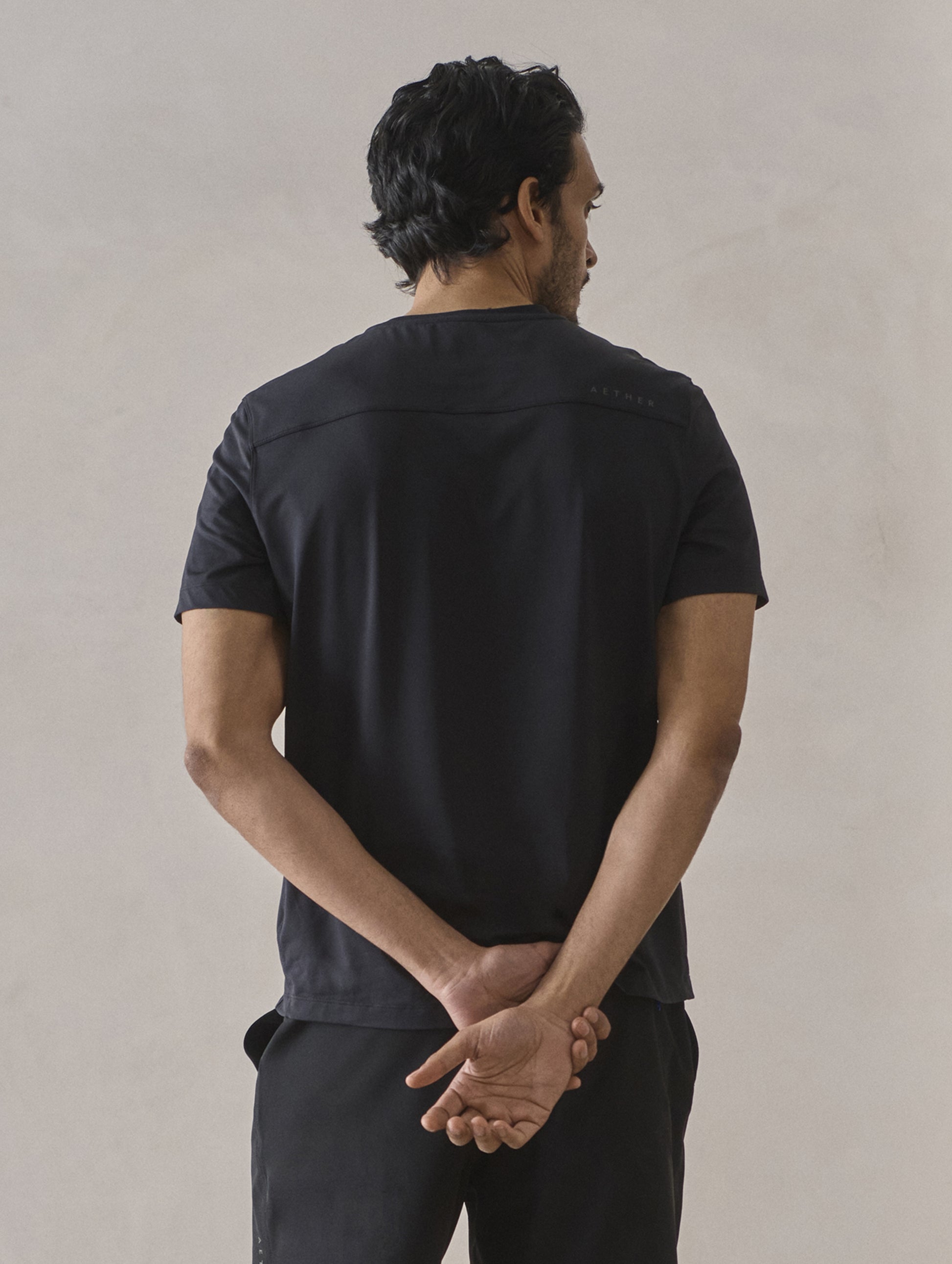 Rear upper-body view of man wearing Adventure Performance Short-Sleeve Tee in Onyx Black from AETHER Apparel.