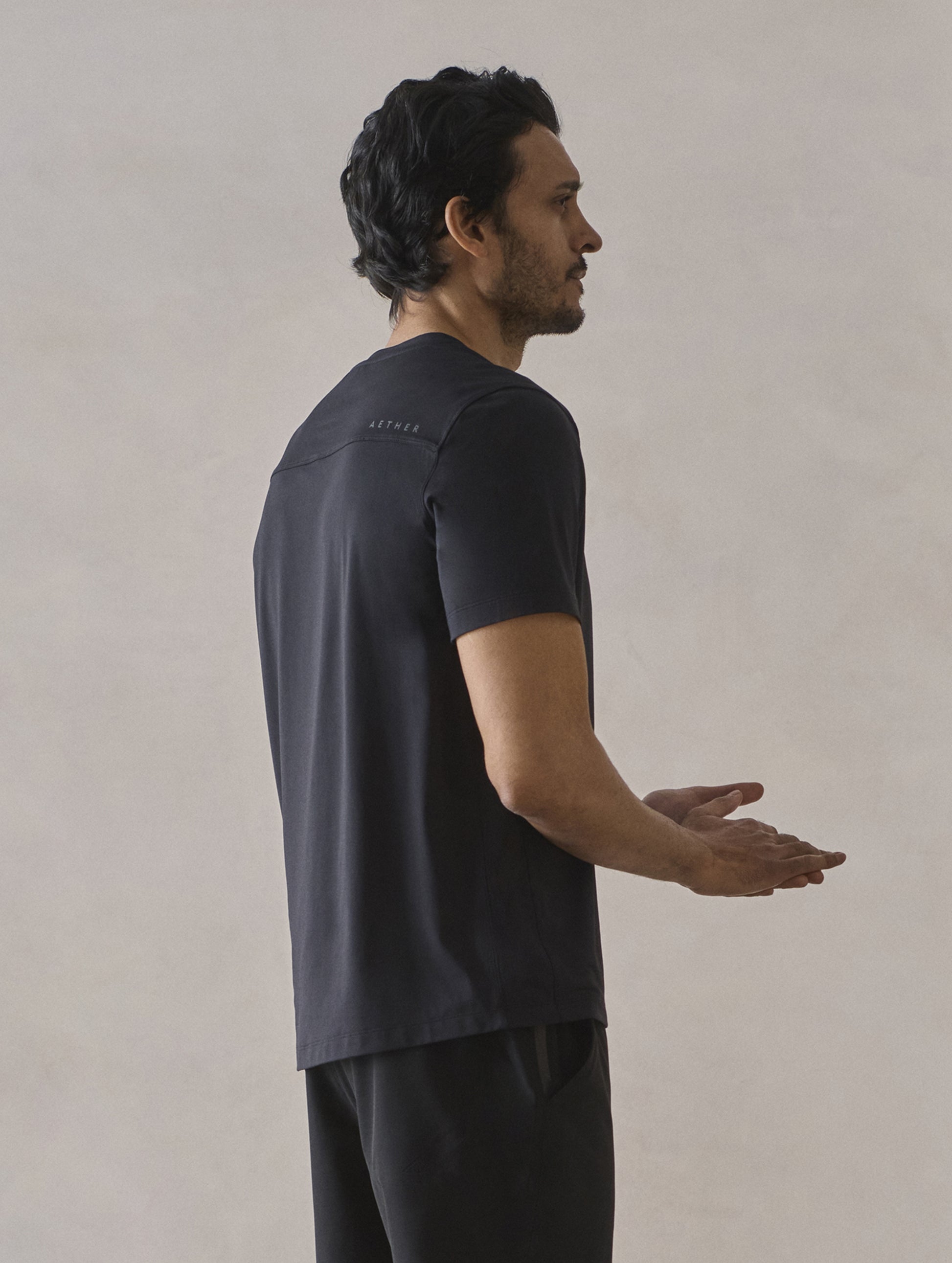 Rear 3/4 upper-body view of man wearing Adventure Performance Short-Sleeve Tee in Onyx Black from AETHER Apparel.