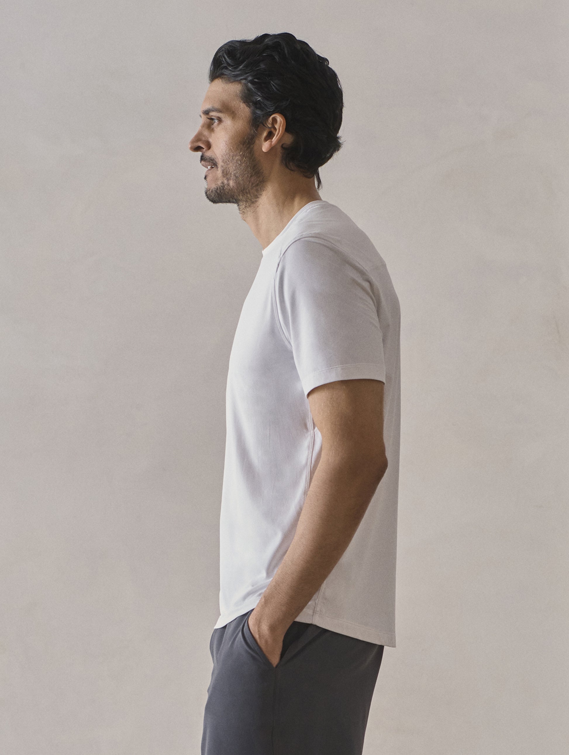 Left side profile upper-body view of man wearing Adventure Performance Short-Sleeve Tee in White from AETHER Apparel.