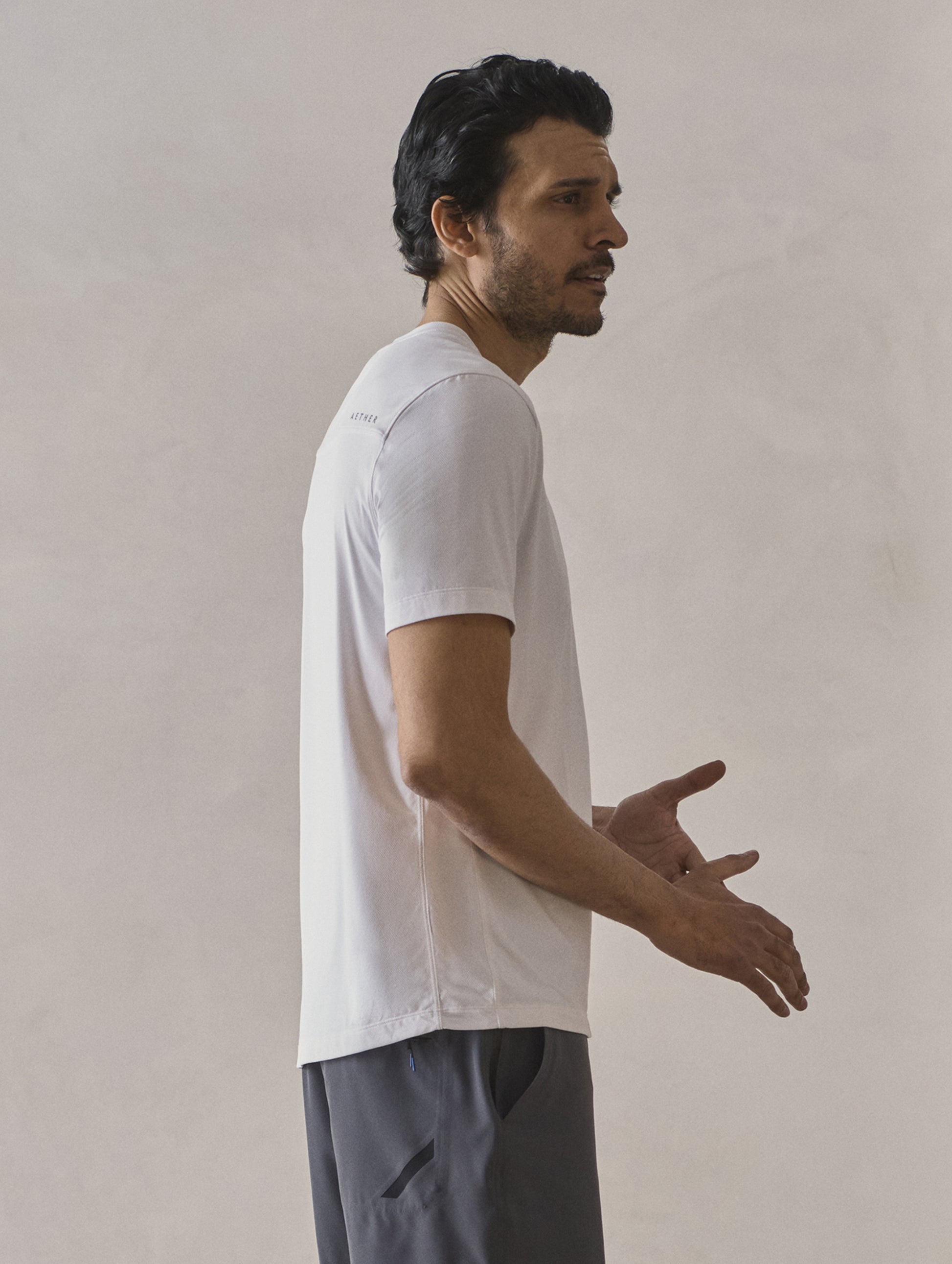 Right side profile upper-body view of man wearing Adventure Performance Short-Sleeve Tee in White from AETHER Apparel.