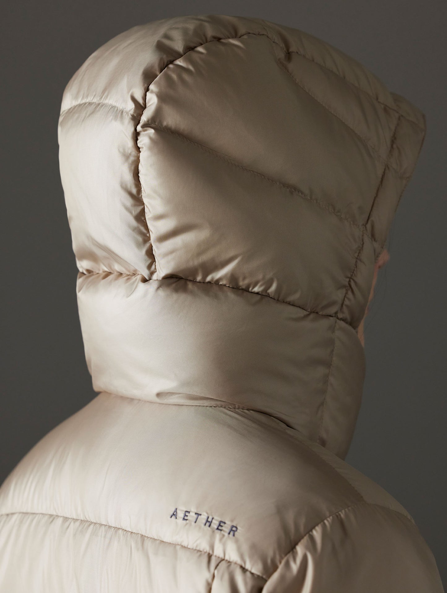 Closeup detailed view of the back of the snap-secured, quilted, 4-piece hood on the Aura Puffer Long in Chinchilla Brown from AETHER Apparel.