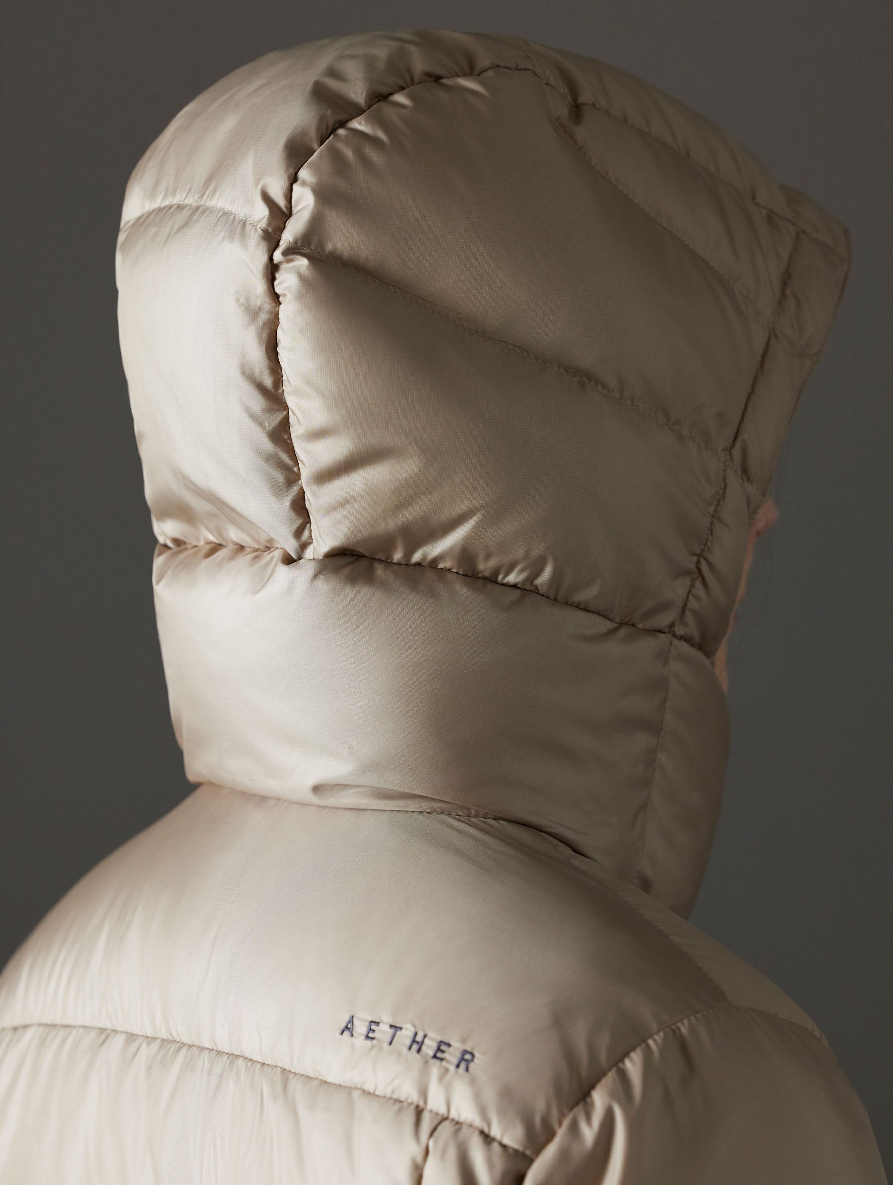 Closeup detailed view of the back of the snap-secured, quilted, 4-piece hood on the Aura Puffer Long in Chinchilla Brown from AETHER Apparel.