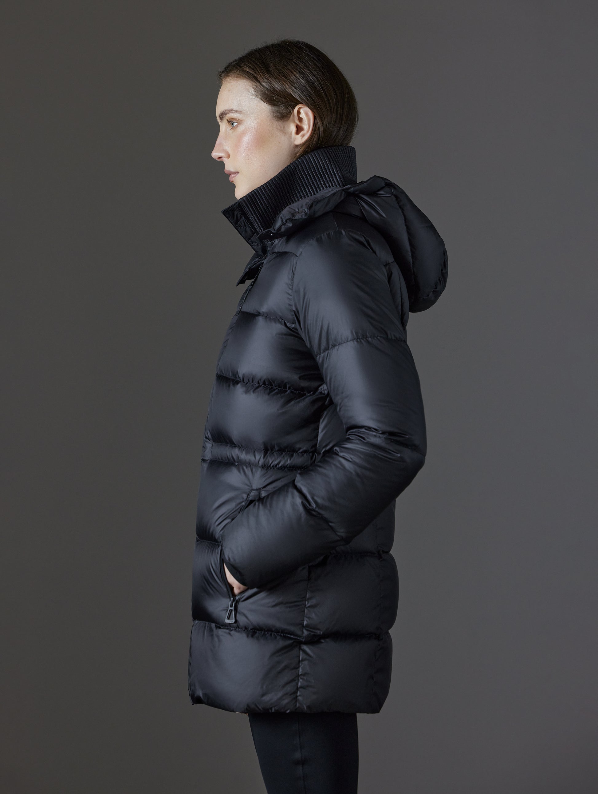 Side profile view of woman wearing Aura Puffer Long in Onyx Black from AETHER Apparel.