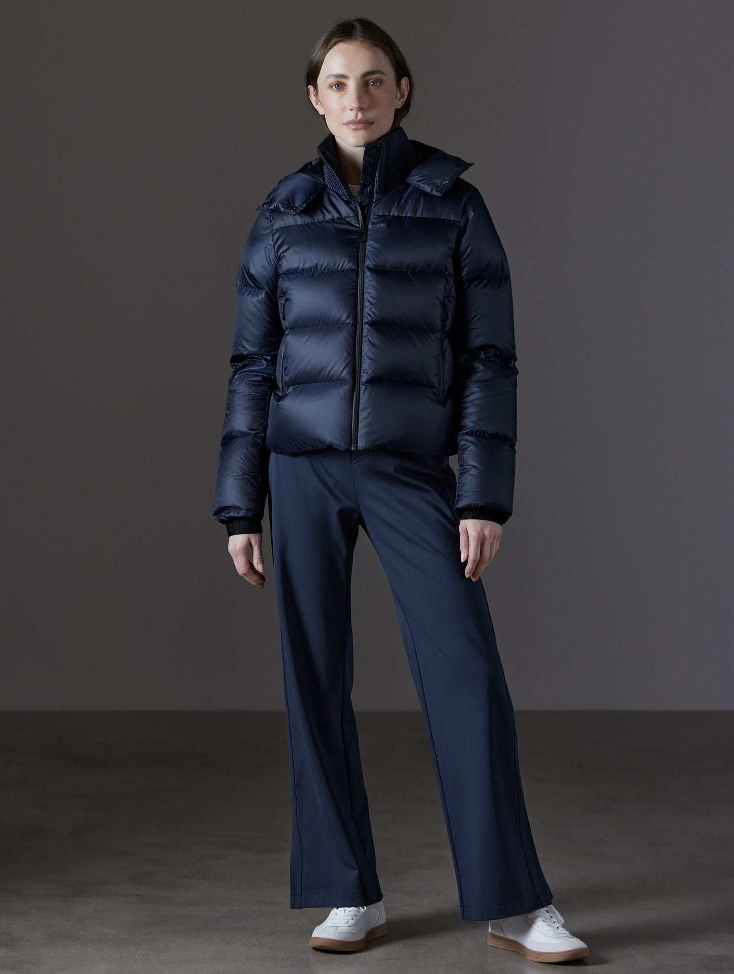 Front full-body view of woman wearing Aura Puffer Jacket in Total Eclipse dark blue from AETHER Apparel.