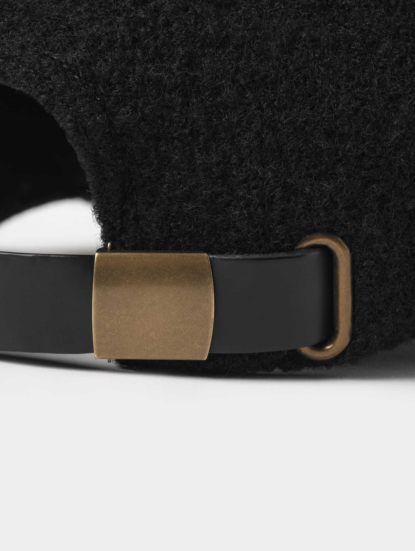 Closeup detailed view of the metal clasp on the back of the Aura Wool Hat in Onyx Black from AETHER Apparel. 