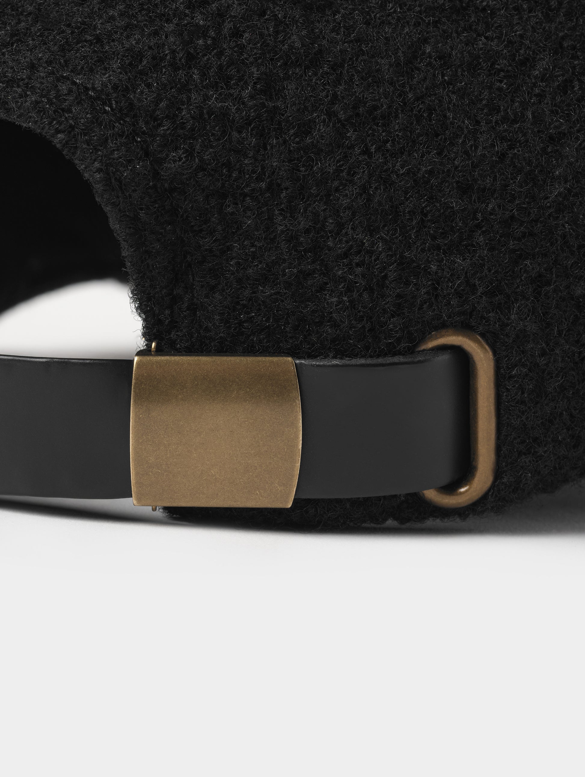 Closeup detailed view of the metal clasp on the back of the Aura Wool Hat in Onyx Black from AETHER Apparel. 