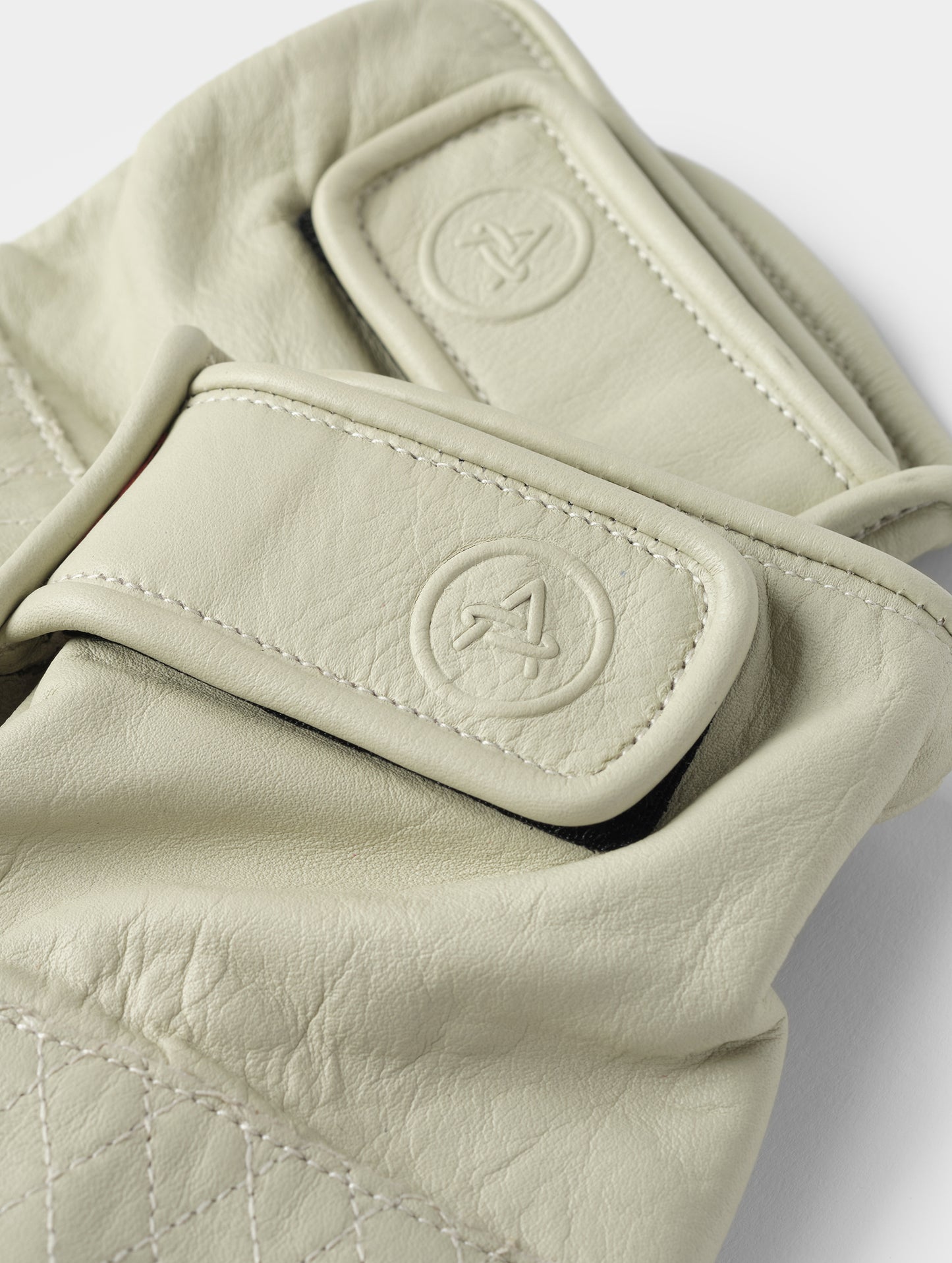 Closeup detailed view of the elasticated wrist and embossed AETHER-branded Velcro pull tab on the Circuit Moto Glove in Basalt from AETHER Apparel.