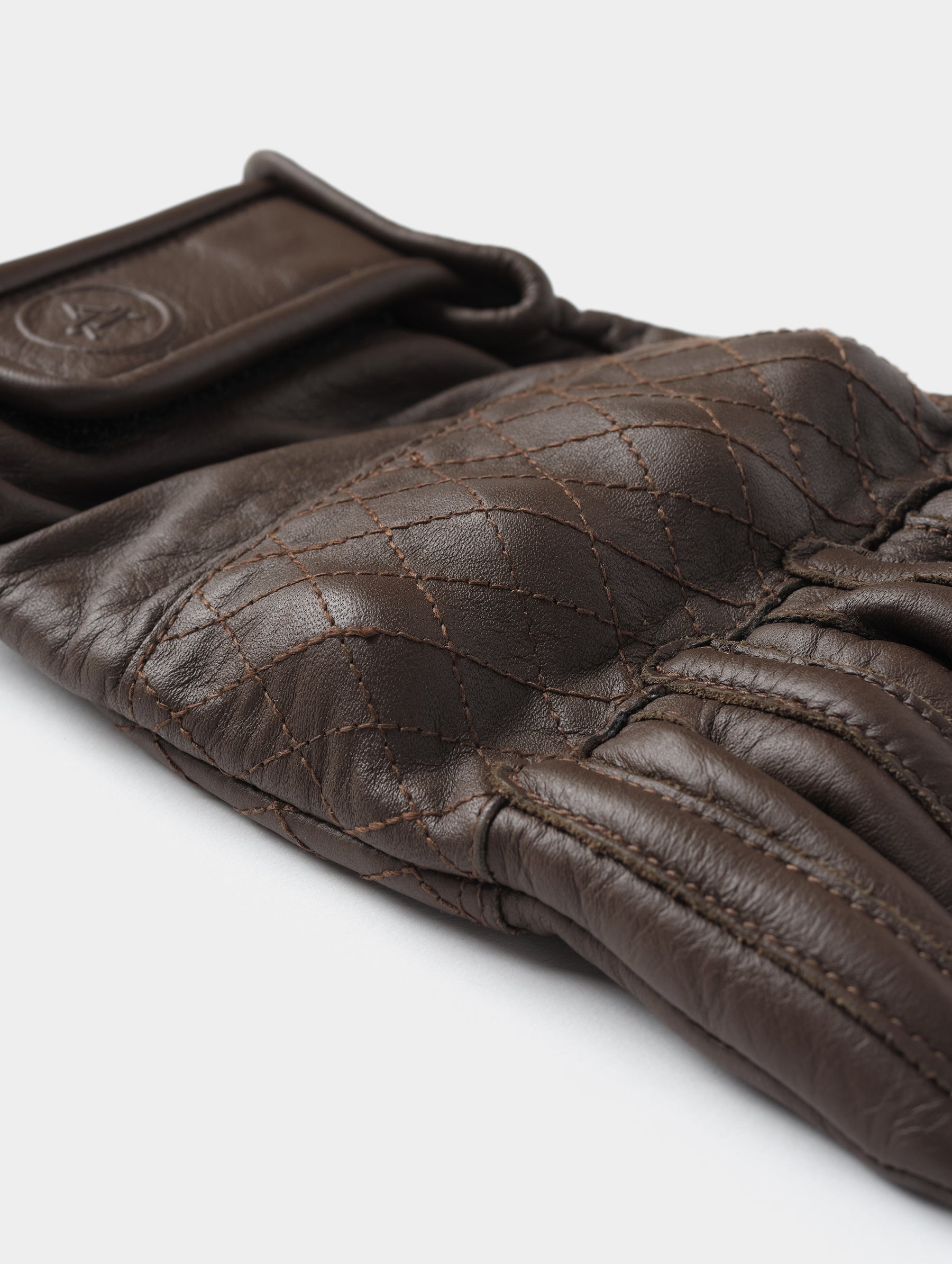 Closeup detailed view of the D3O-armored quilted knuckle on the Circuit Moto Glove in Espresso Brown from AETHER Apparel.