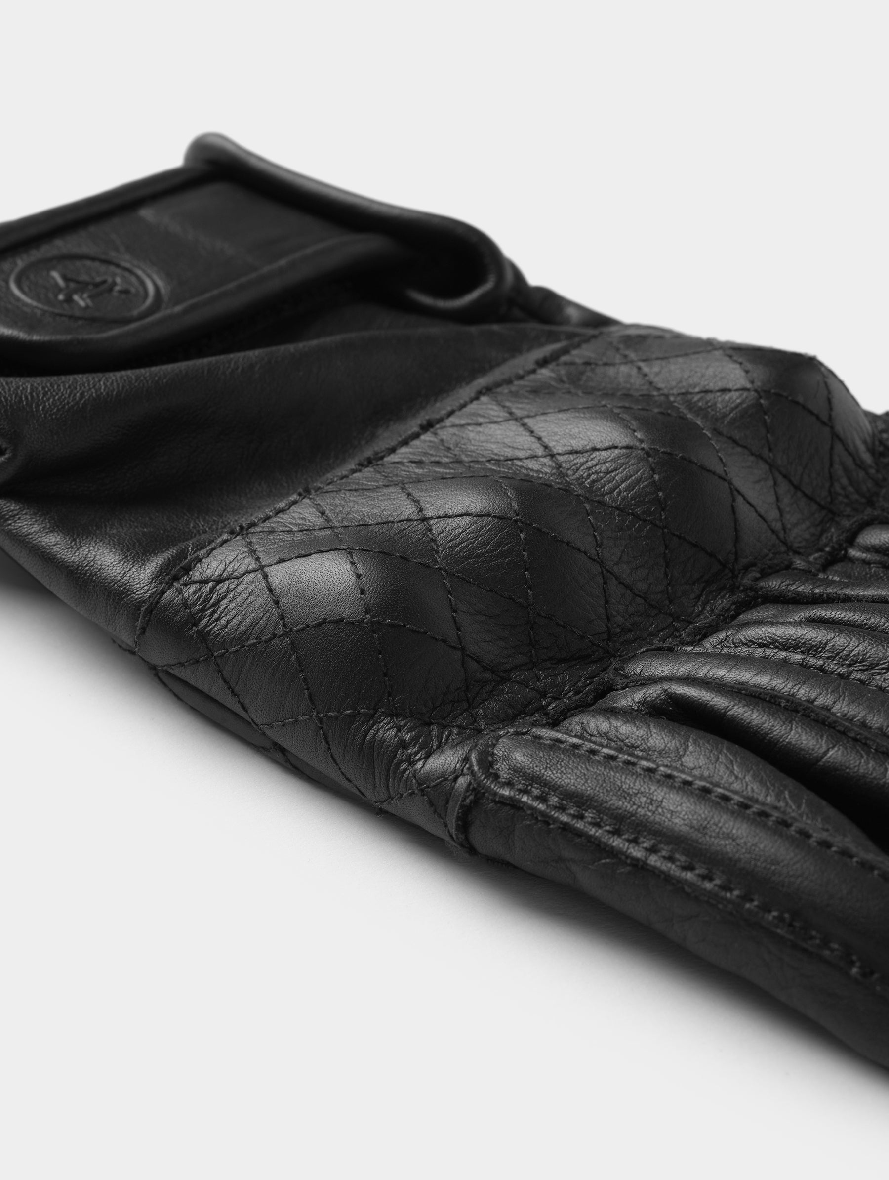 Closeup detailed view of the D3O-armored quilted knuckle on the Circuit Moto Glove in Onyx Black from AETHER Apparel.