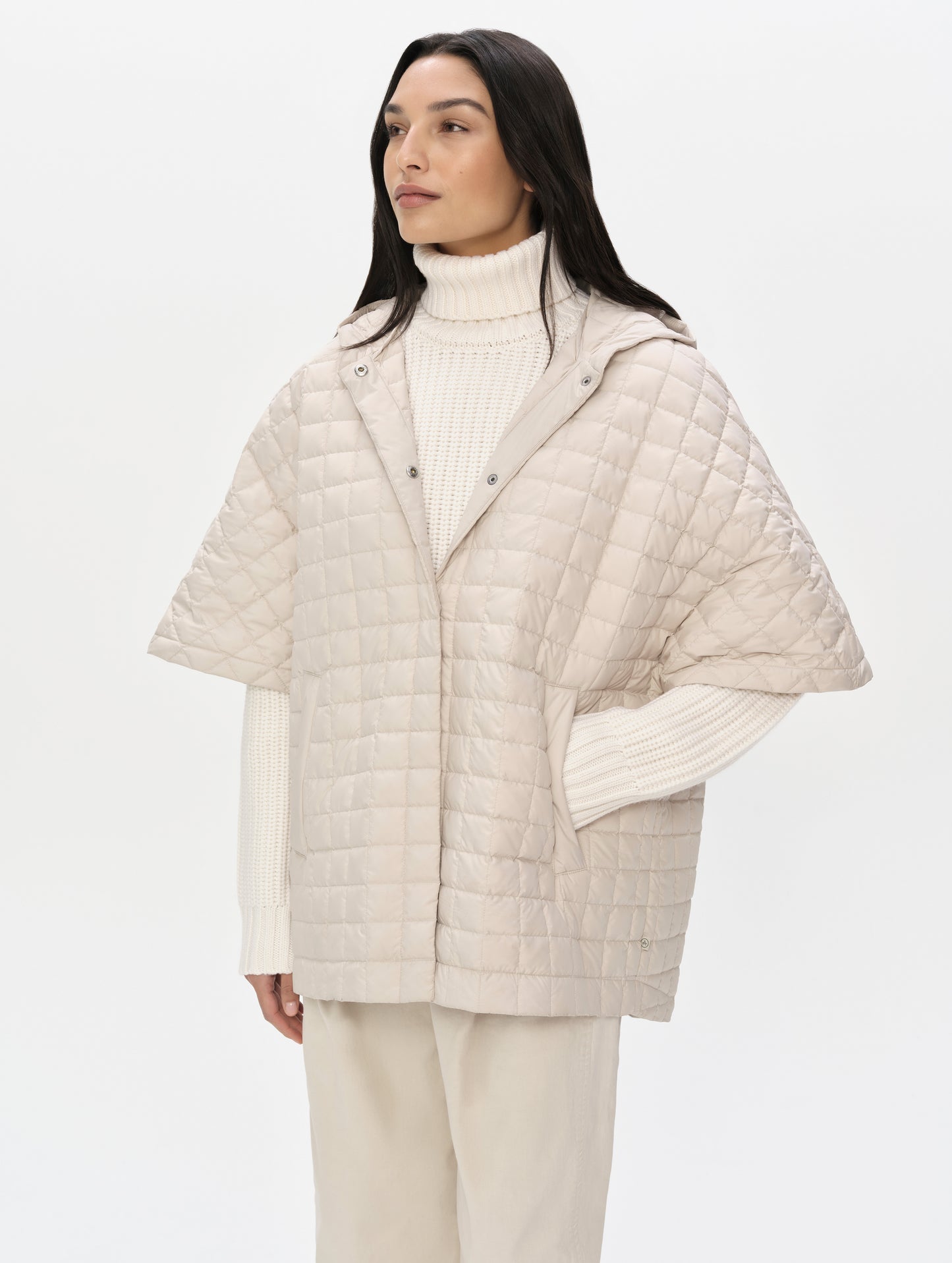 Front upper-body view of woman with hood down wearing the Bardo Hooded Poncho in Bone from AETHER Apparel.