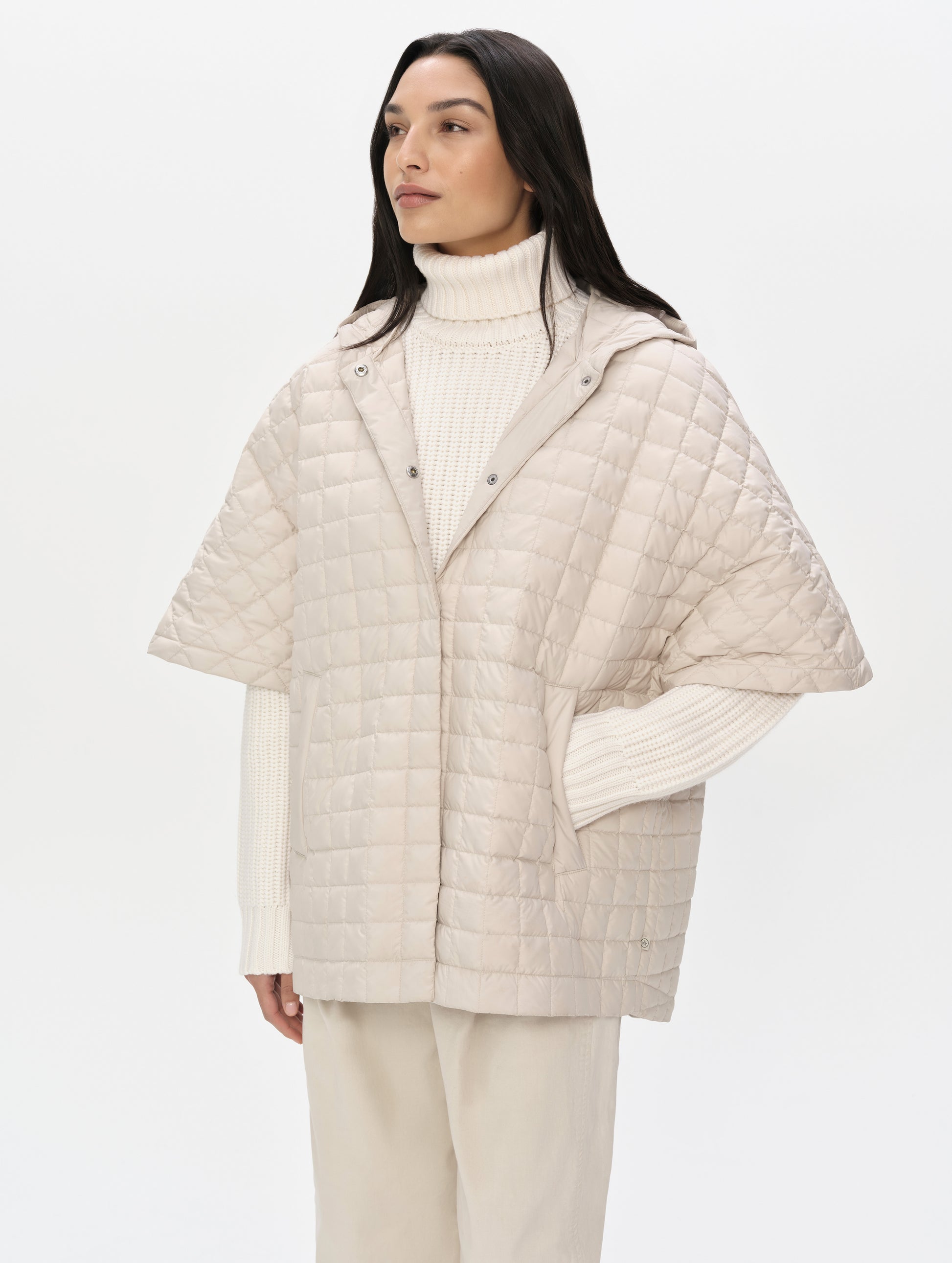Front upper-body view of woman with hood down wearing the Bardo Hooded Poncho in Bone from AETHER Apparel.