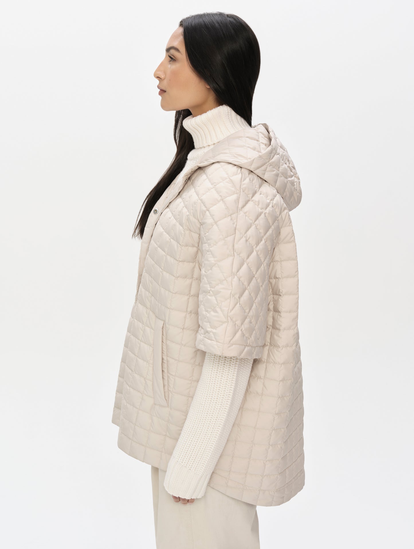 Side profile upper-body view of woman with hood down wearing the Bardo Hooded Poncho in Bone from AETHER Apparel.