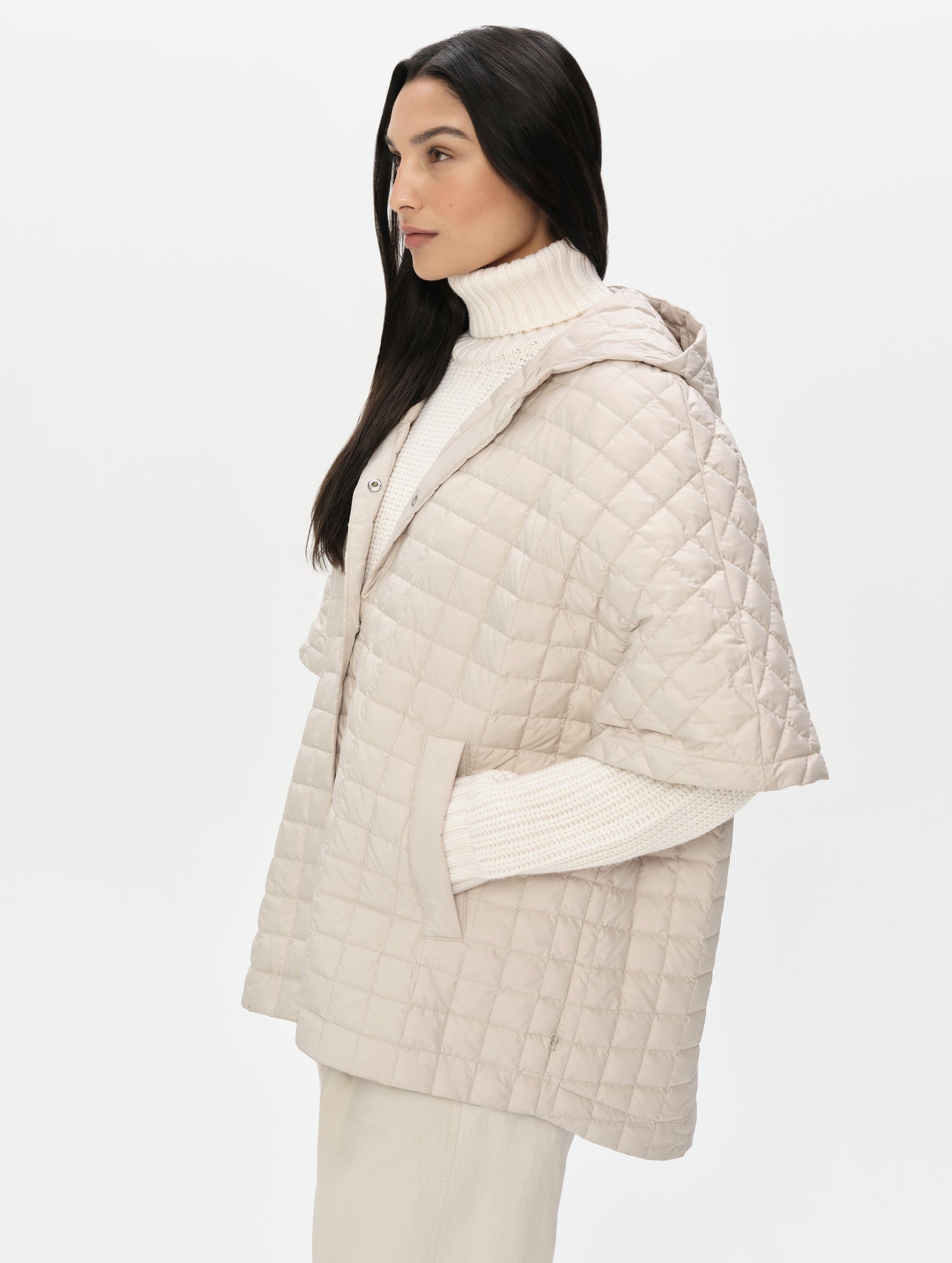 Front, angled upper-body view of woman with hood down wearing the Bardo Hooded Poncho in Bone from AETHER Apparel.
