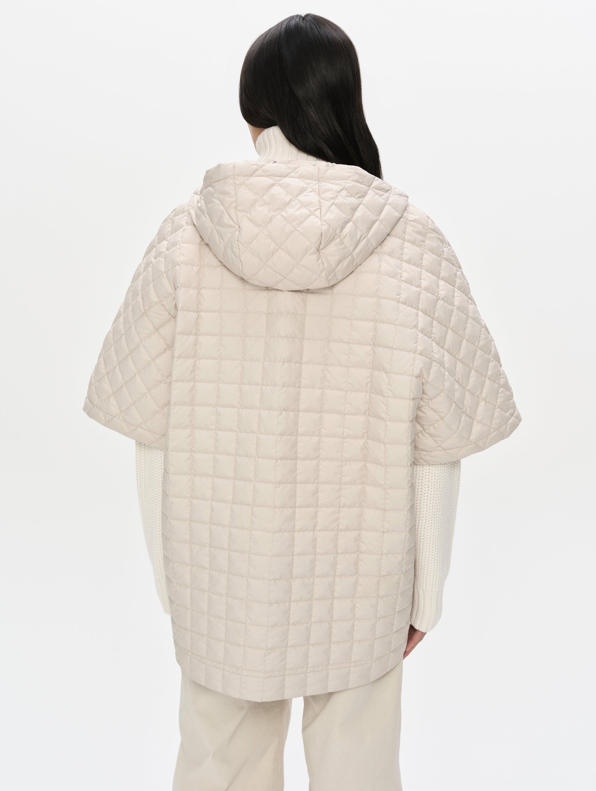Rear upper-body view of woman with hood down wearing the Bardo Hooded Poncho in Bone from AETHER Apparel.