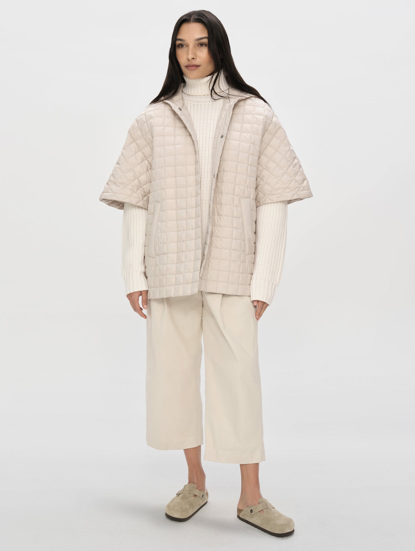 Front, full-body view of woman with hood down wearing the Bardo Hooded Poncho in Bone from AETHER Apparel.