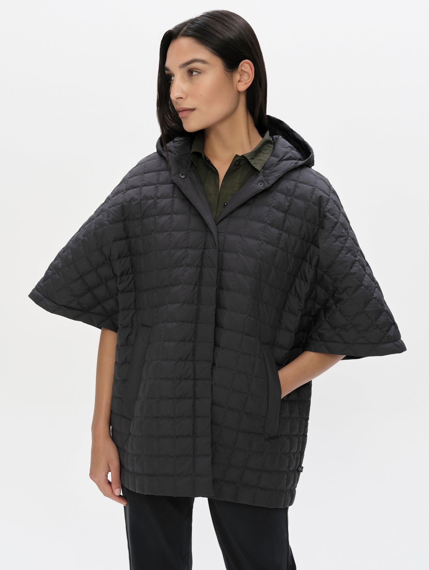 Front upper-body view of woman with hood down wearing the Bardo Hooded Poncho in Onyx Black from AETHER Apparel.