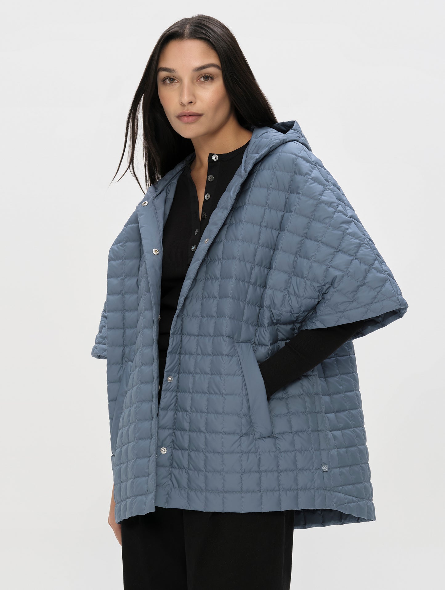 Front, angled upper-body view of woman with hood down wearing the Bardo Hooded Poncho in Portal Blue from AETHER Apparel.